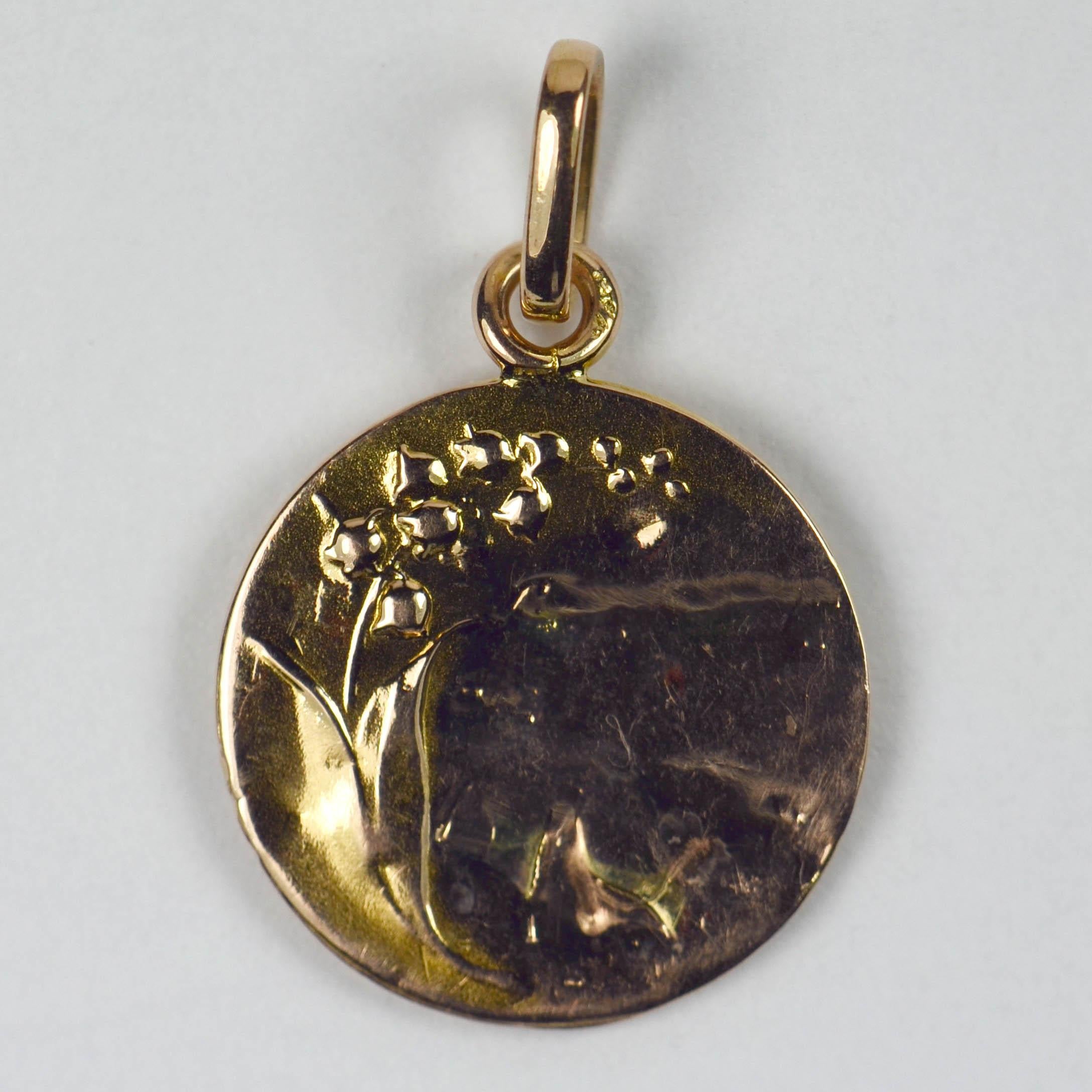 A French 18 karat (18K) yellow gold charm pendant designed as a medal depicting the Virgin Mary to one side, with a lily of the valley to the reverse. Marked ‘Virgo Maria’ and signed E. Dropsy. Stamped with the French eagle’s head for 18 karat