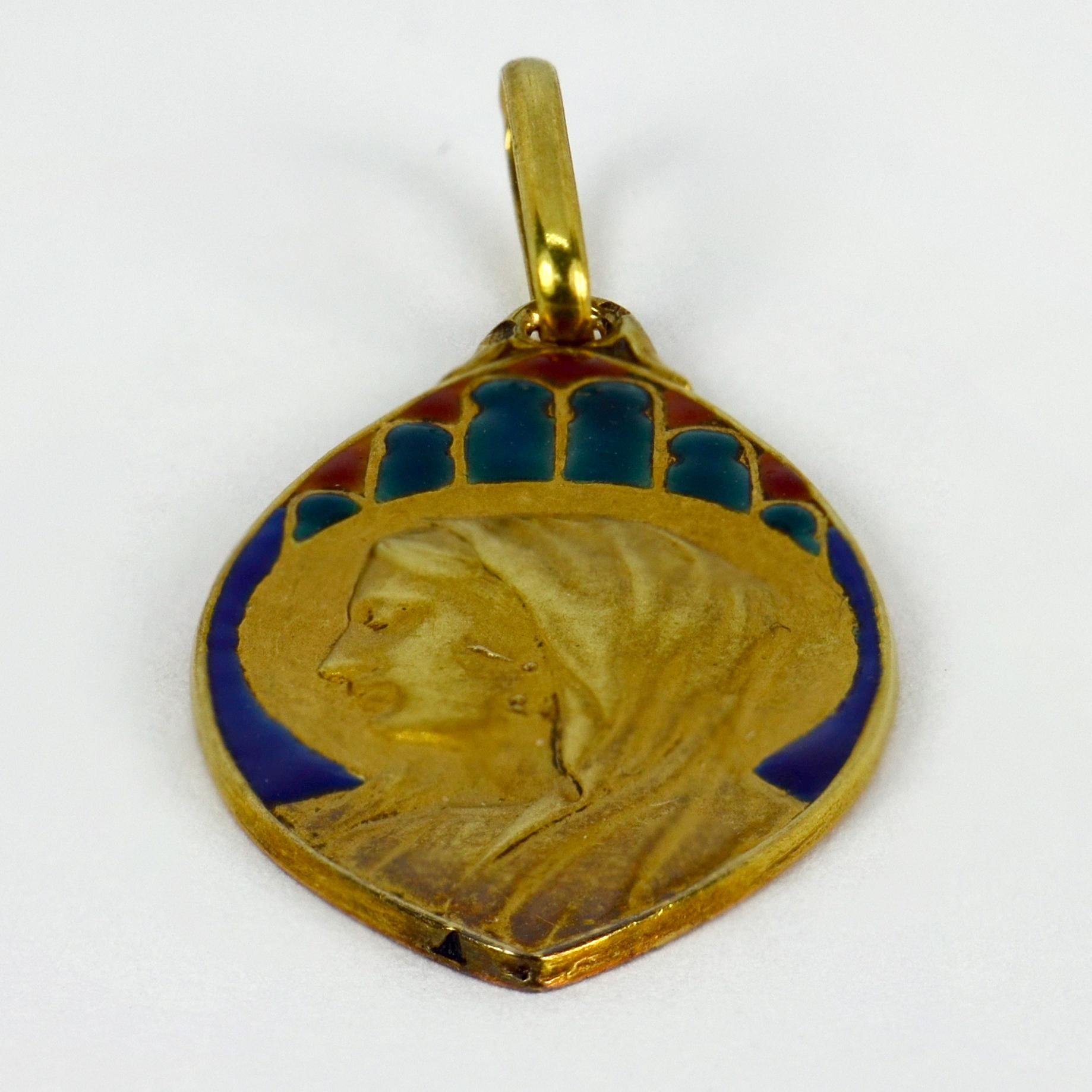 A French 18 karat (18K) yellow gold charm pendant designed as a navette shaped medal depicting the Virgin Mary to an enamel ground resembling a stained glass window. Stamped with the eagle’s head for 18 karat gold and French
