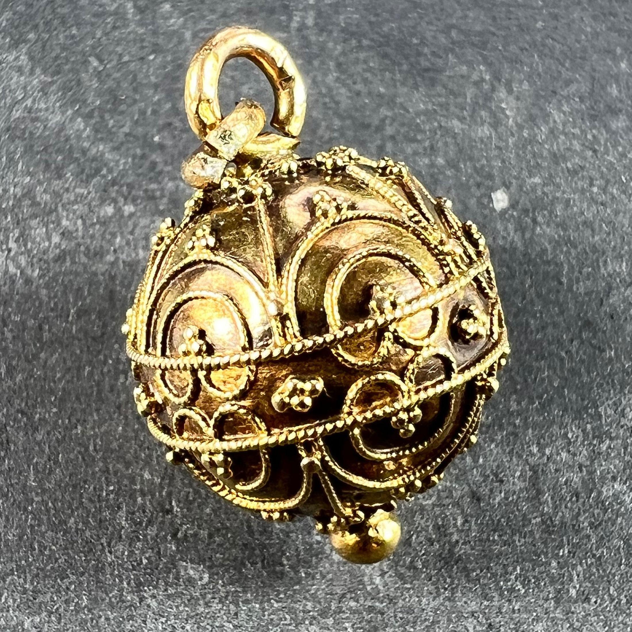 A French 18 karat (18K) yellow gold charm pendant designed as a sphere with gold filgree decoration. Stamped with the eagle's head mark for 18 karat gold and French manufacture, along with an unknown maker's mark.

Dimensions: 2 x 1.32 x 1.32
