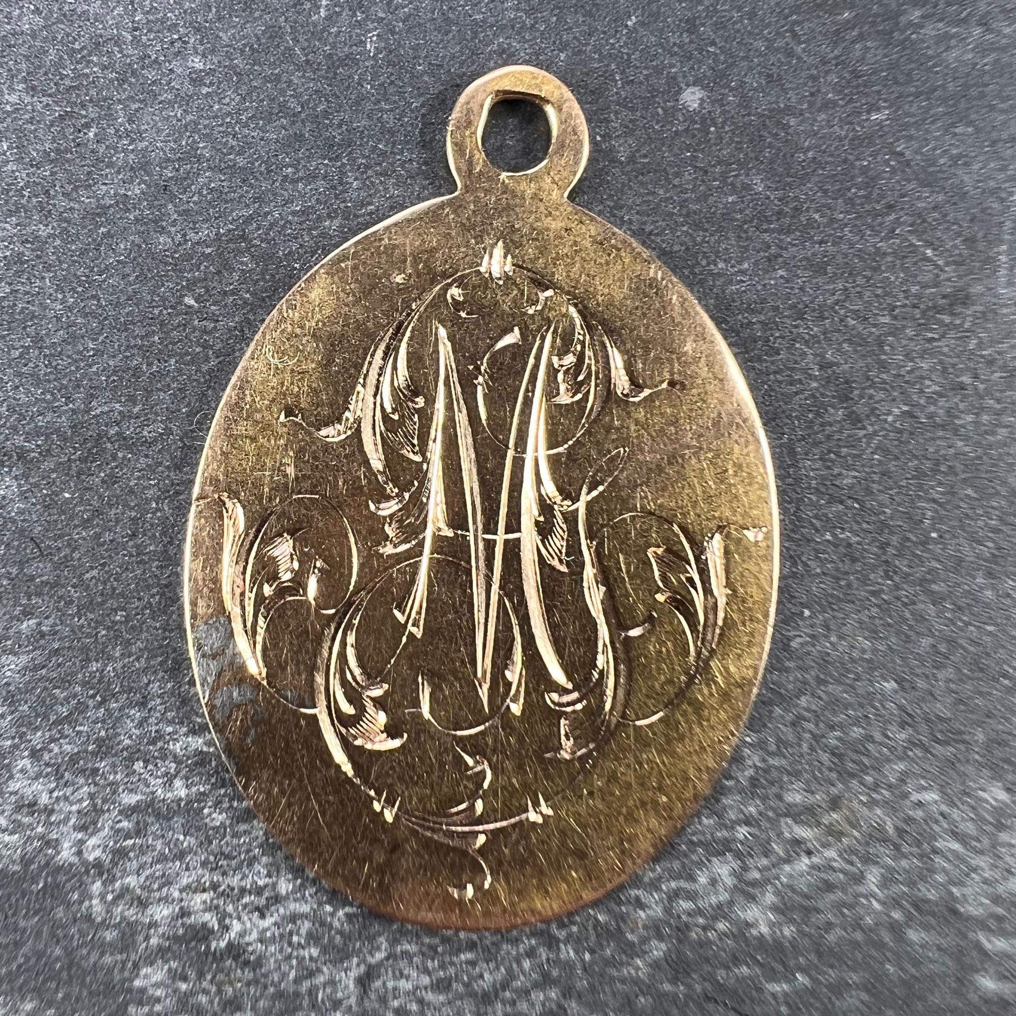 A French 18 karat (18K) yellow gold charm pendant designed as an oval medal detailing the monogram MG or GM in engraved script. Engraved to the reverse with the date '16 Juillet 1905'. Unmarked but tested for 18 karat gold.

Dimensions: 2.8 x 2 x