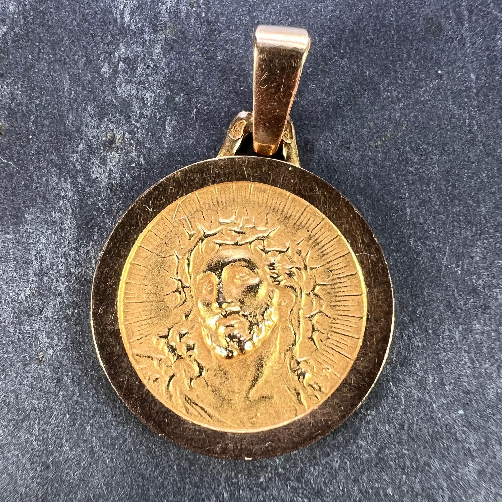 A French 18 karat (18K) yellow gold charm pendant designed as a round medal depicting Christ wearing the Crown of Thorns, with a radiant halo surrounding him. Stamped with the eagle’s head for 18 karat gold and French manufacture, along with an