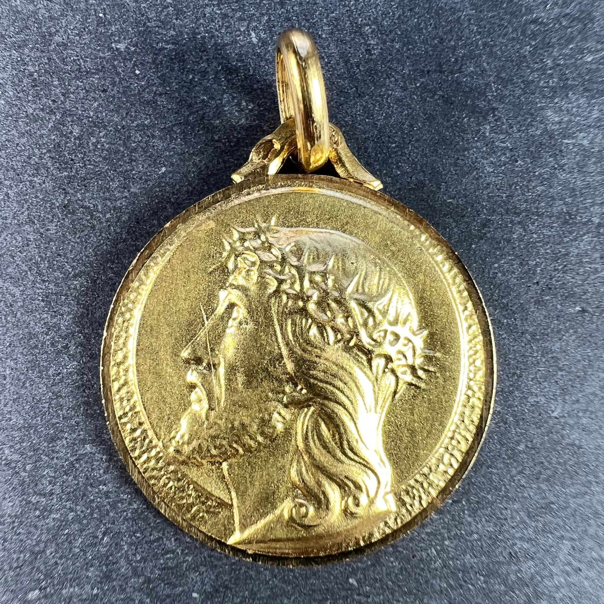 A French 18 karat (18K) yellow gold charm pendant designed as a round medal depicting the profile of Christ wearing the Crown of Thorns, with a halo surrounding him. Stamped with the eagle’s head for 18 karat gold and French manufacture, along with