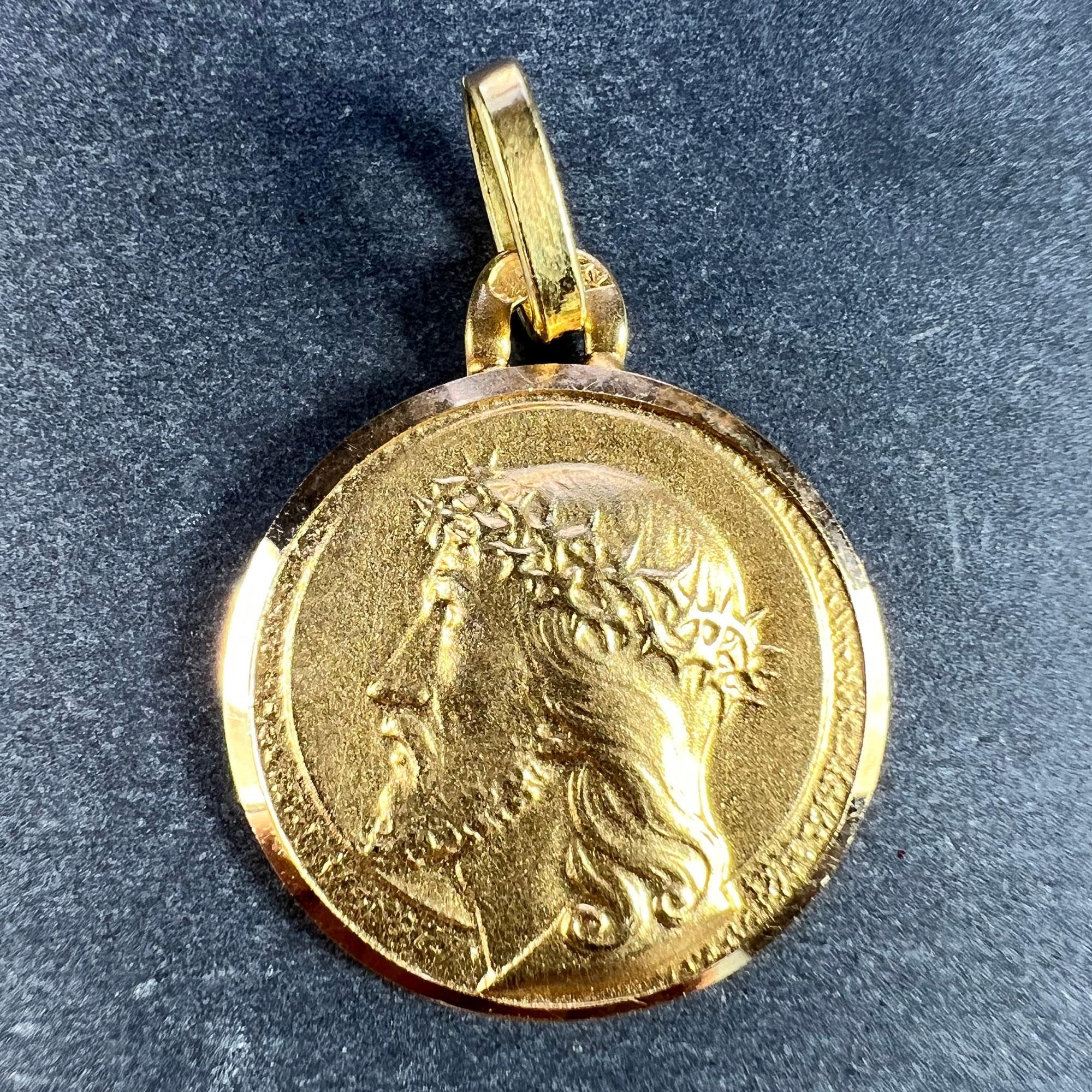 A French 18 karat (18K) yellow gold charm pendant designed as a round medal depicting the profile of Christ wearing the Crown of Thorns, with a halo surrounding him. Stamped with the eagle’s head for 18 karat gold and French manufacture, along with