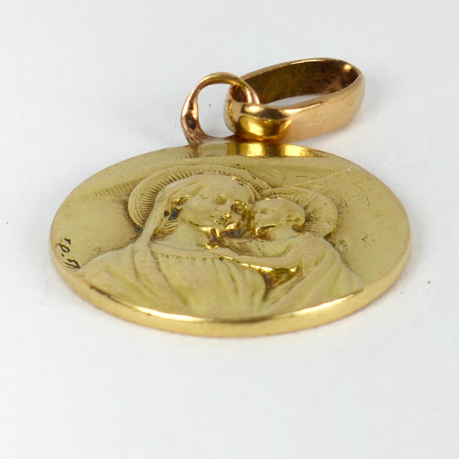 A French 18 karat (18K) yellow gold charm pendant designed as medal depicting the Madonna and child on one side, the other depicting Jesus with a sacred heart, framed by the words ‘Cor Jesu Eurcharisticum Miserere Nobis’ (Eucharistic heart of Jesus,