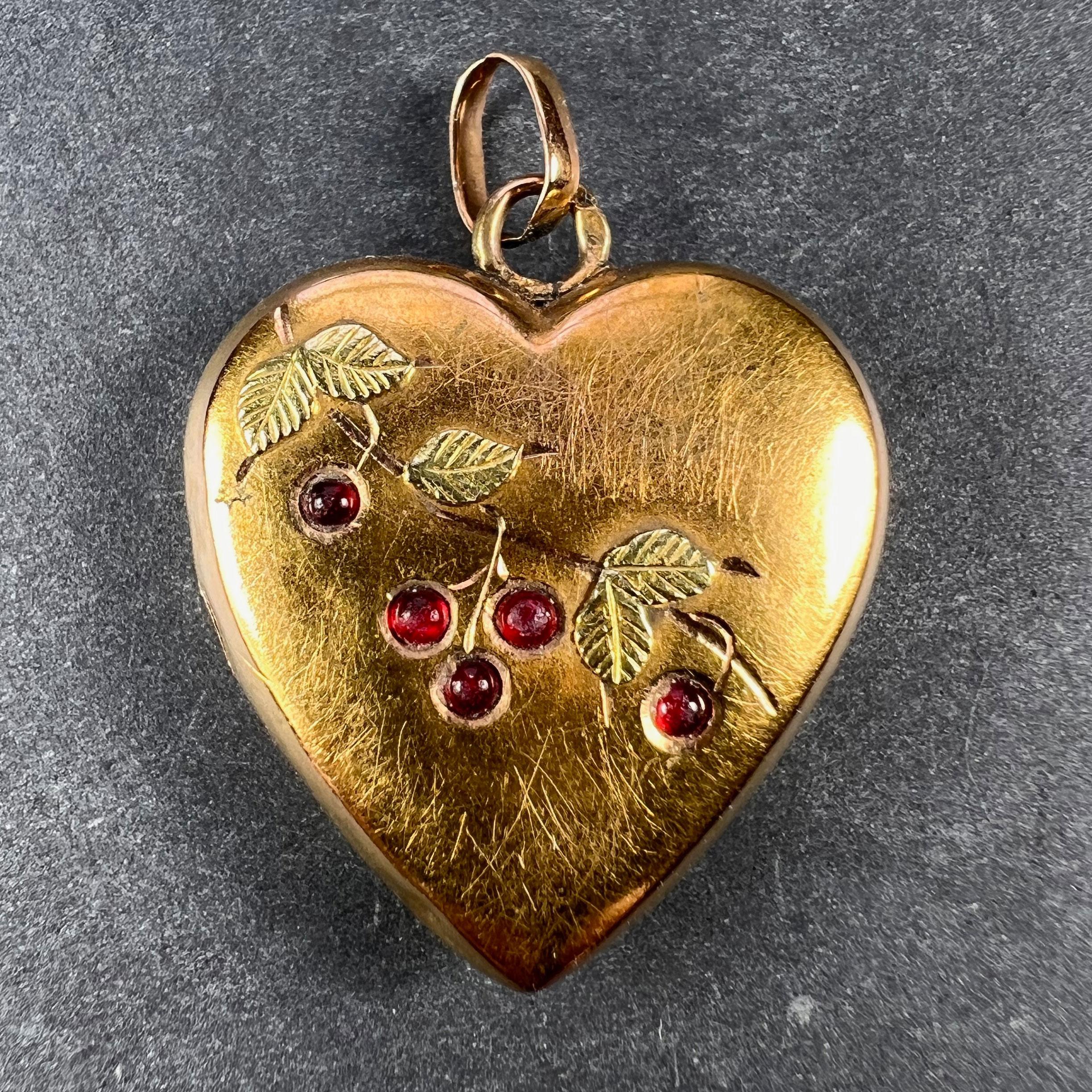A French 18 karat (18K) yellow gold charm pendant designed as a love heart engraved with a branch of cherries with green gold leaves, set with red round cabochon cut pastes (man-made glass). Stamped with the eagle's head for 18 karat gold and French