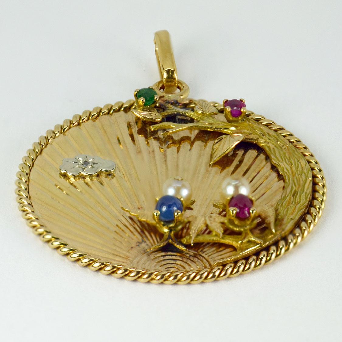 A French 18 karat (18K) yellow gold pendant depicting a pair of lovebirds on a branch in front of the setting sun. Set with a faceted emerald, ruby and diamond, a cabochon ruby and sapphire and two cultured pearls. 

Engraved to the reverse ‘Brulure