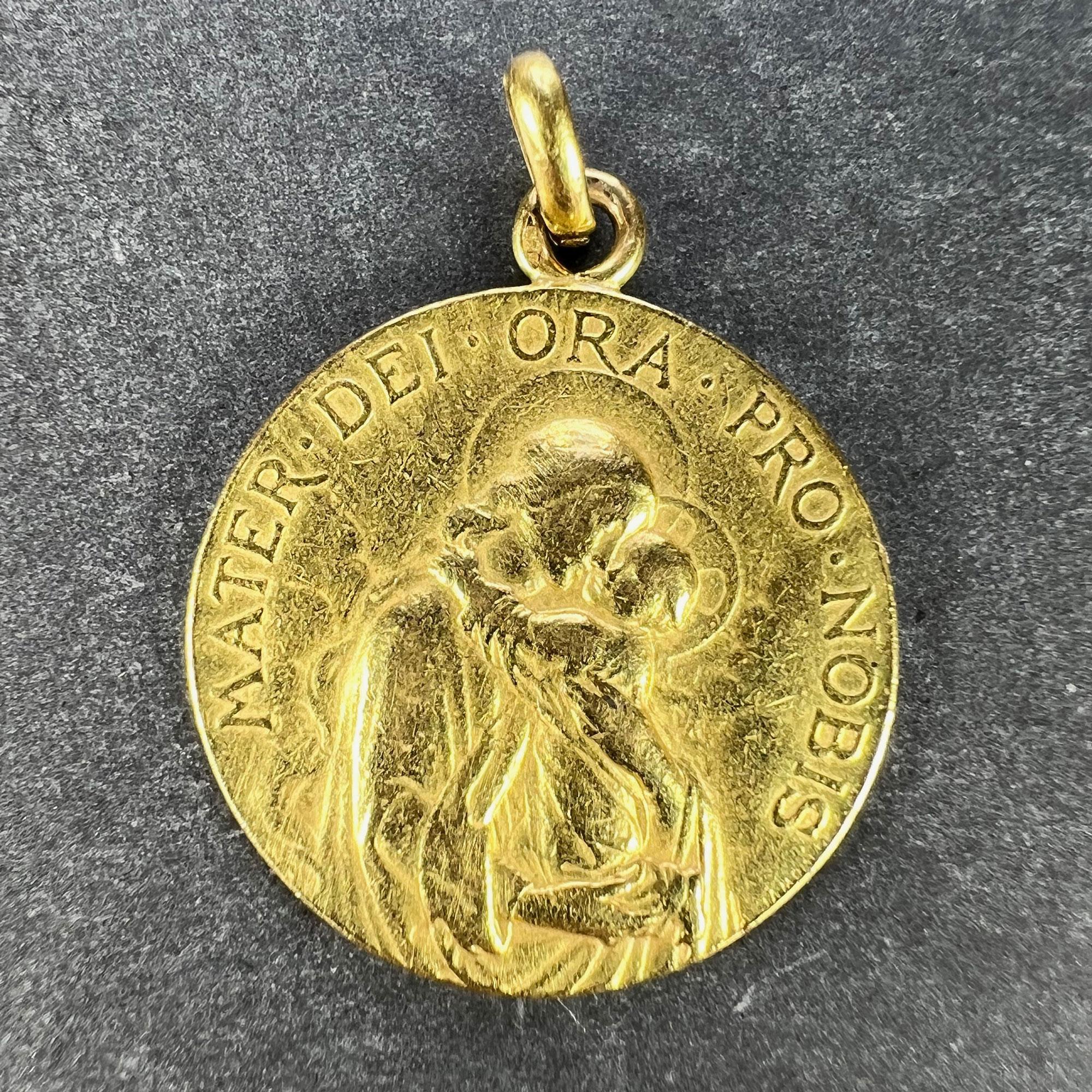 A French 18 karat (18K) yellow gold charm pendant designed as a round medal with a relief of the Madonna and Child surrounded by clouds, with the Latin motto 'MATER DEI ORA PRO NOBIS' (Mother of God pray for us) above. The reverse depicting a branch