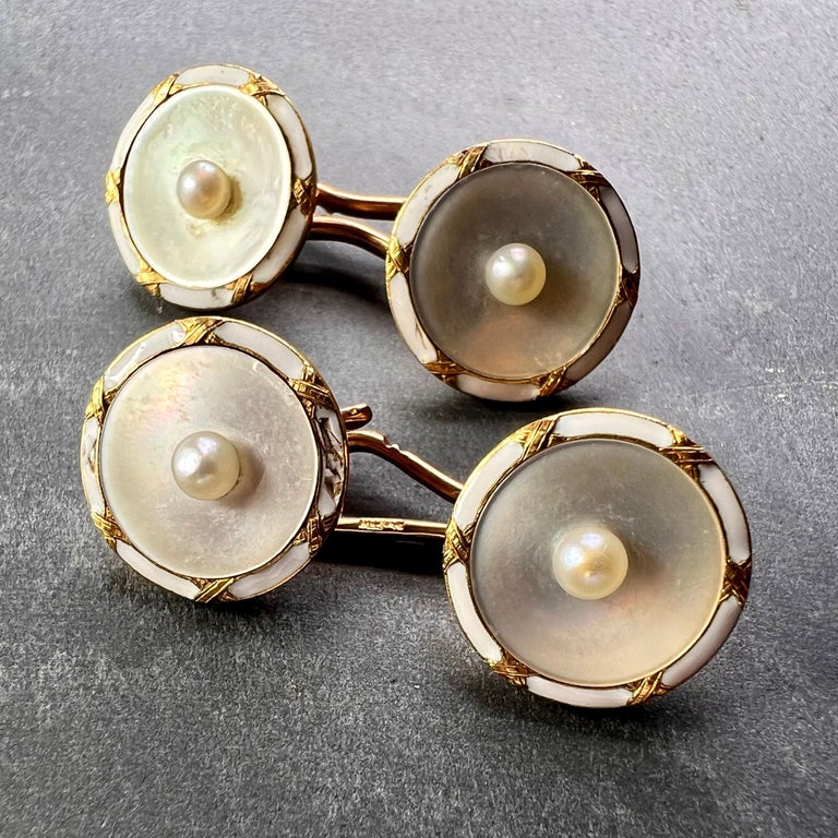 A pair of French 18K (18 karat) yellow gold cufflinks designed as a pair of convex mother-of-pearl discs set to the centre with a natural seed pearl and edged with white enamel. Stamped with the eagle’s head for French manufacture and 18 karat gold
