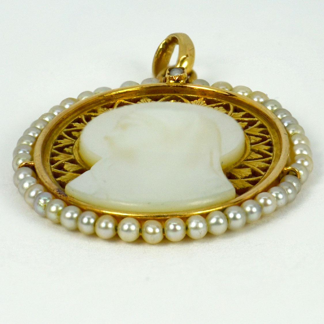 A French 18 karat (18K) yellow gold charm pendant designed as an oval representing the Virgin Mary as a Mother-of-Pearl cameo set in a pierced frame of roses, surrounded by 43 natural white seed pearls with a single seed pearl collet set to the top.