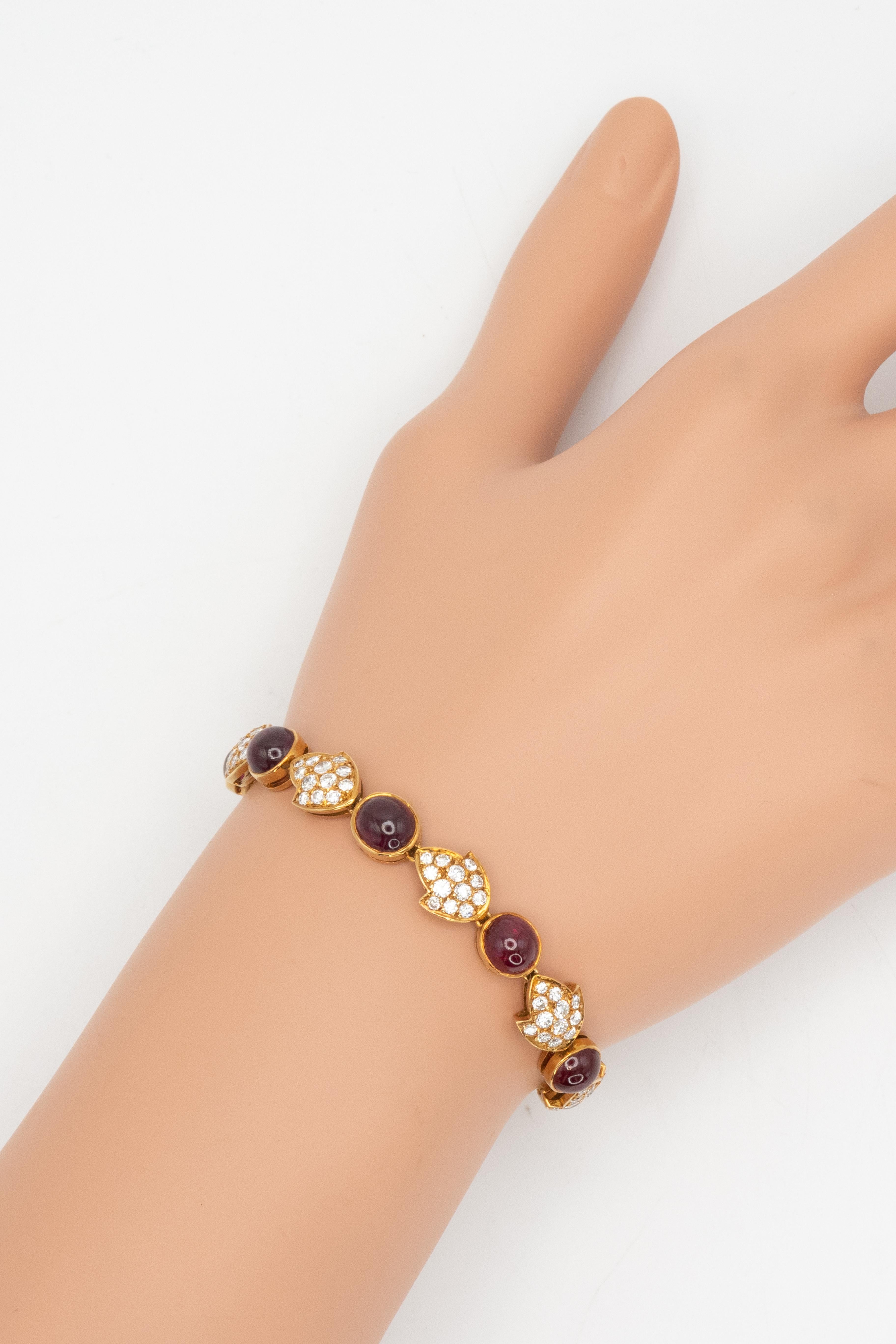 Ce bracelet français en or jaune 18 carats présente une alternance de rubis cabochons rouges et de diamants sertis en pavé dans des maillons stylisés en forme de feuilles. Le bracelet présente environ 13,0 carats de cabochons de rubis translucides,