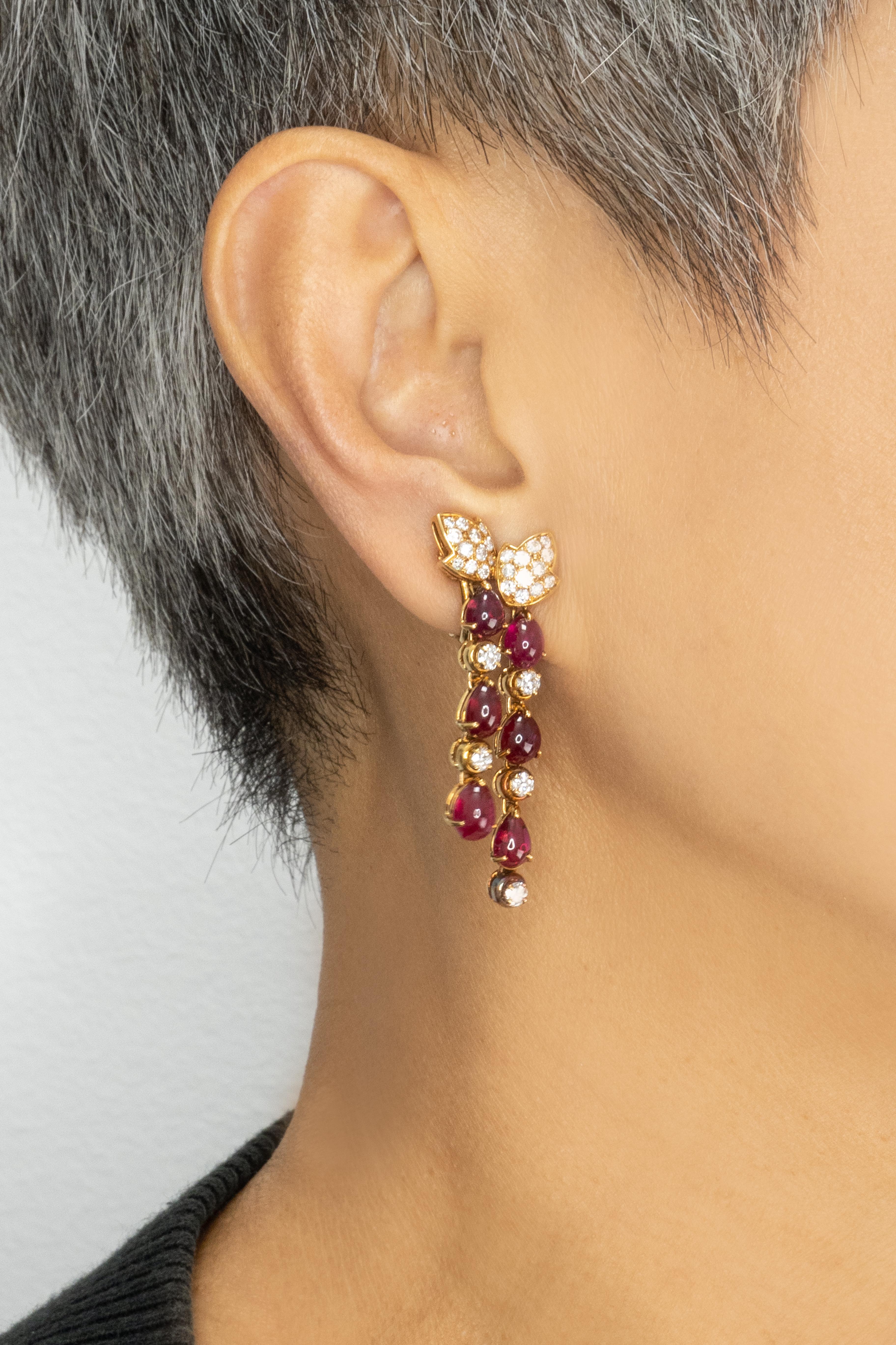 Élégantes et vibrantes, ces boucles d'oreilles françaises sont réalisées en or jaune 18 carats et présentent environ 10,0 carats de rubis cabochon rouge, accentués par des diamants taille brillant totalisant environ 2,4 carats, de couleur E-F et de