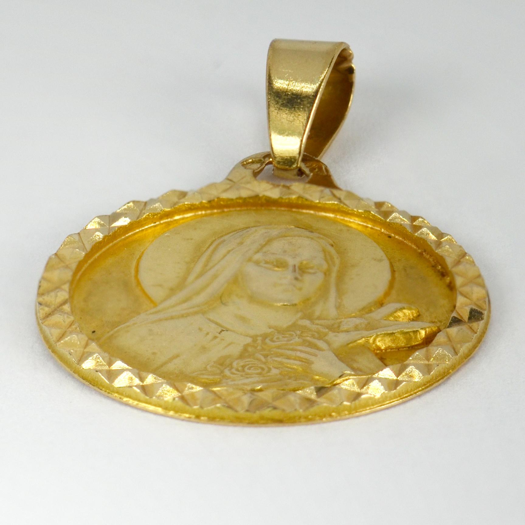 A French 18 karat (18K) yellow gold charm pendant designed as a medal depicting Saint Therese with a halo holding a crucifix and some roses, the frame faceted to give further visual interest. Stamped with the eagles head for 18 karat gold and French