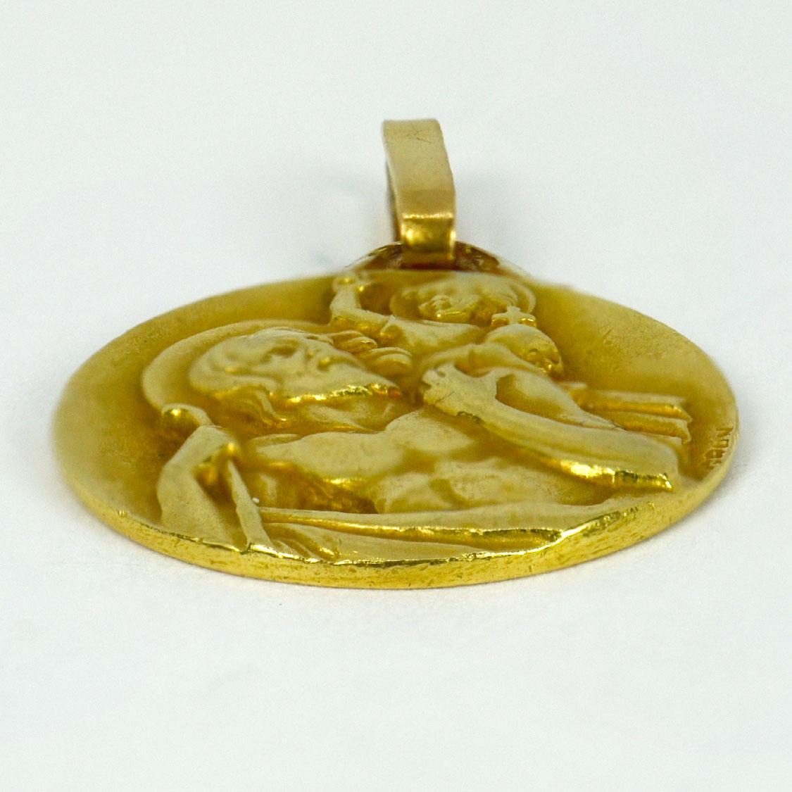 A French 18 karat (18K) yellow gold charm pendant designed as a disc representing Saint Christopher carrying the infant Christ. Signed Grun, stamped with the eagle's head for French manufacture and 18 karat gold with an unknown maker’s mark.