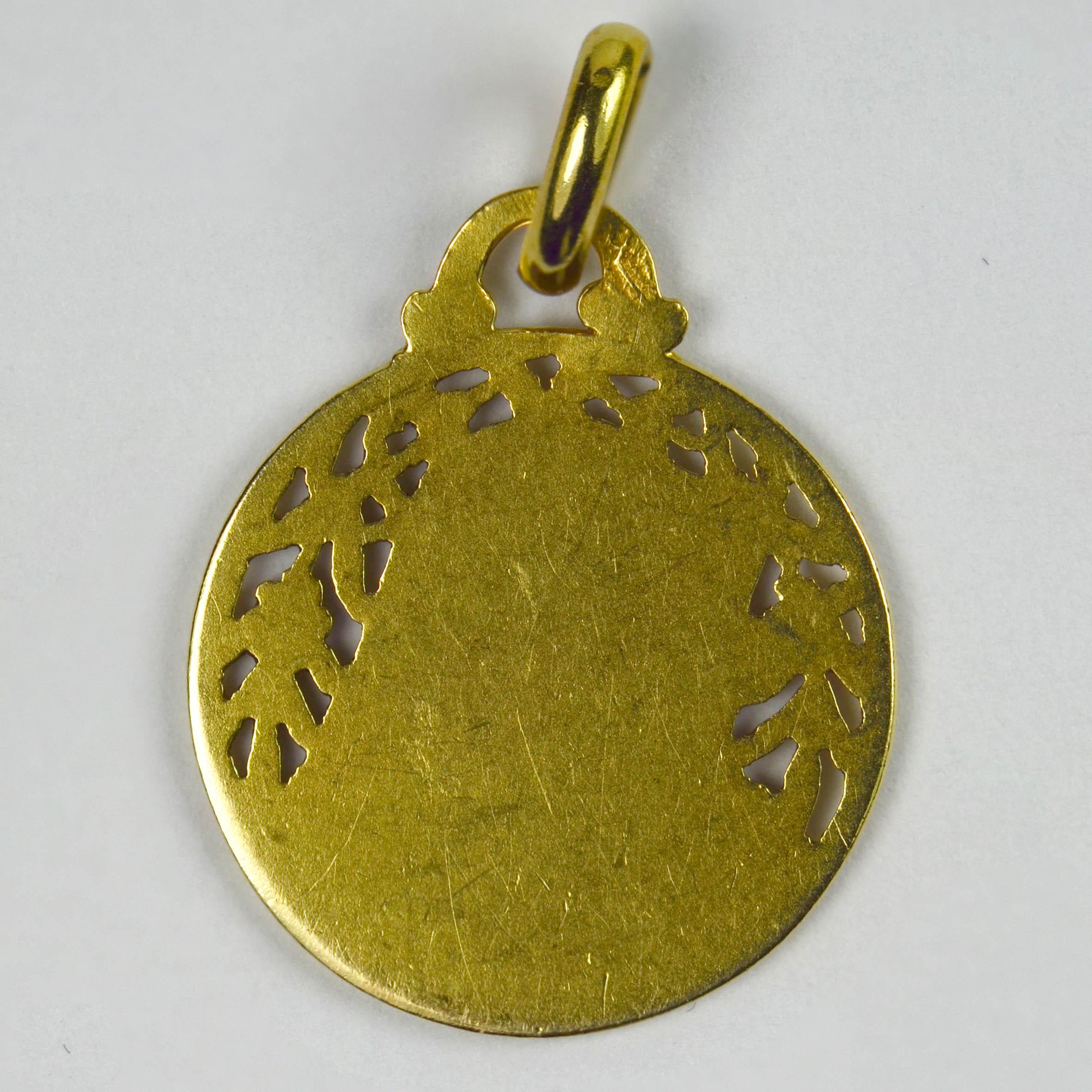 A French 18 karat (18K) yellow gold charm pendant designed as a pierced and engraved medal depicting the Virgin Mary against a field of flowers and leaves. Stamped with the eagle's head for 18 karat gold and French manufacture.

Dimensions: 2.5 x