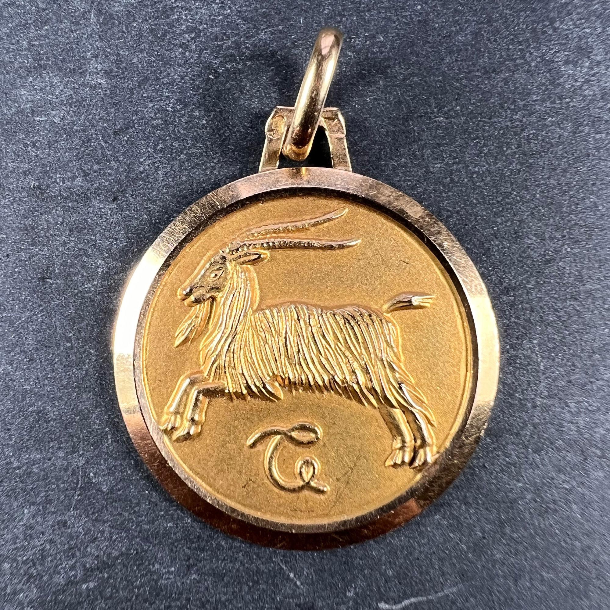 A French 18 karat (18K) yellow gold charm pendant designed as the Zodiac sign of Capricorn in yellow gold within a circular frame. The zodiac symbol for the sign is an artistic version of the lesser known Capricorn symbol. Stamped with the eagle’s