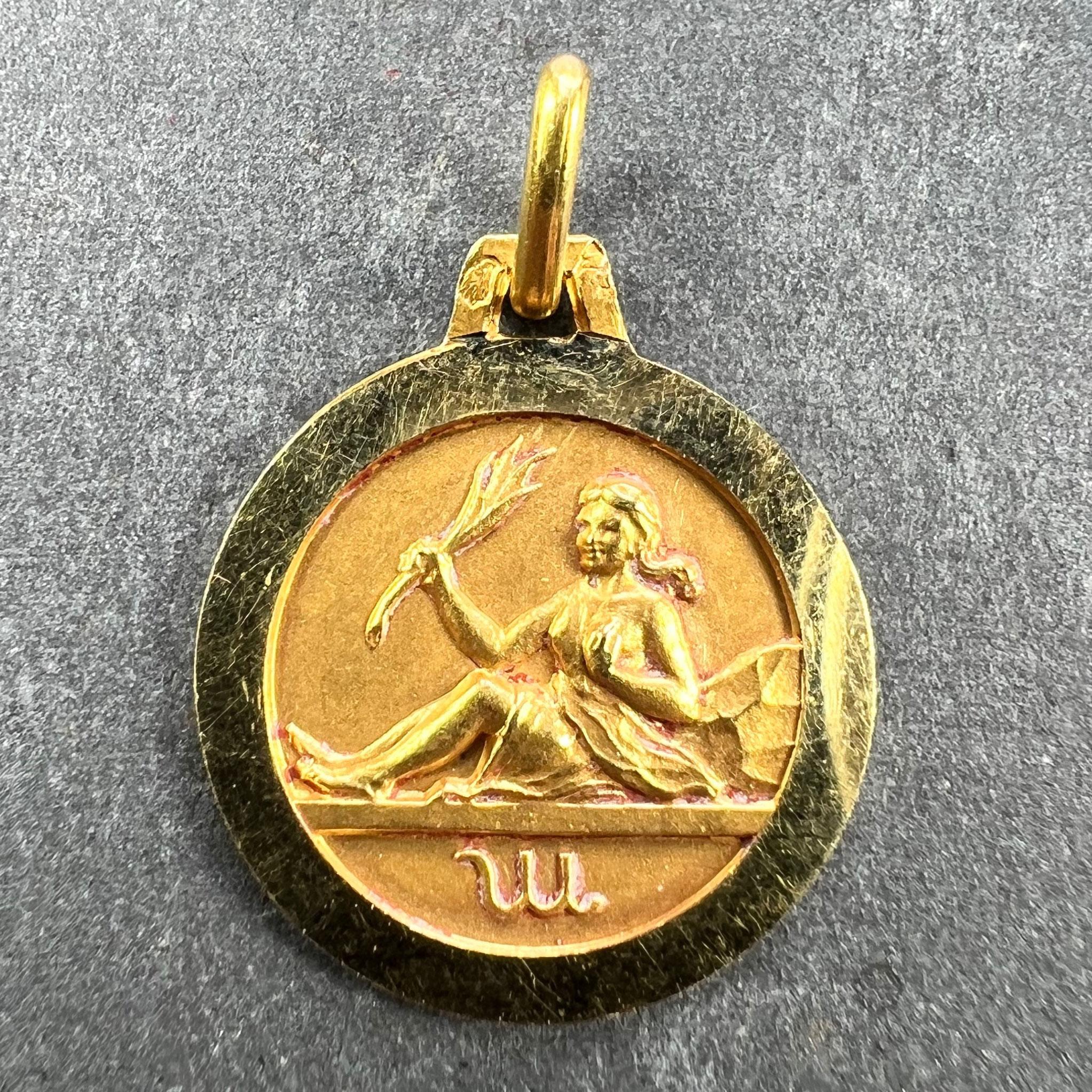 A French 18 karat (18K) yellow gold charm pendant designed as the Zodiac sign of Virgo in yellow gold within a circular frame. Stamped with the eagle’s head punch mark for 18 karat gold and French manufacture and an unknown maker's