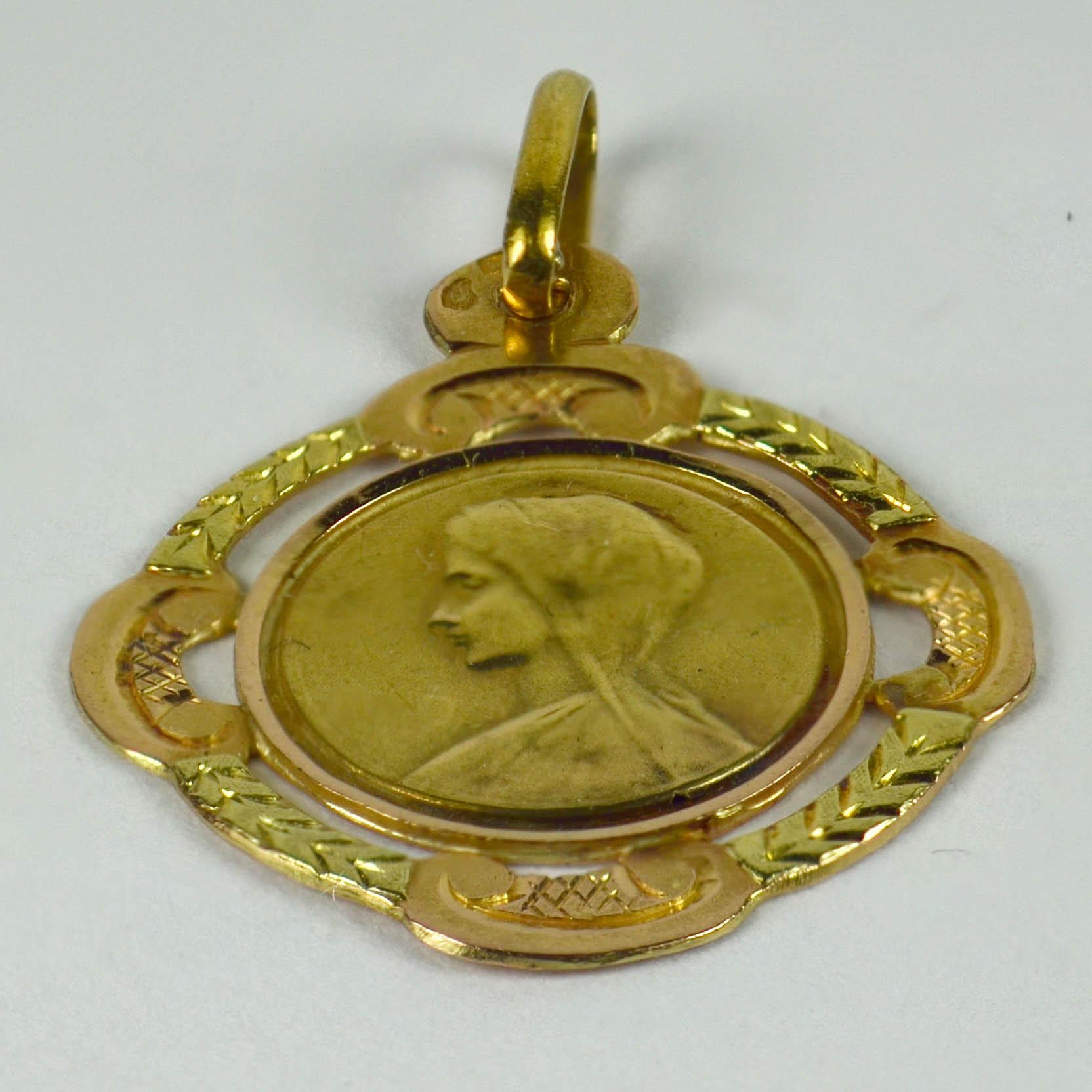 A French 18 karat (18K) yellow gold charm pendant designed as a pierced and engraved medal depicting the Virgin Mary within a yellow and rose gold frame. Stamped with the eagle's head for 18 karat gold and French manufacture with unknown maker's