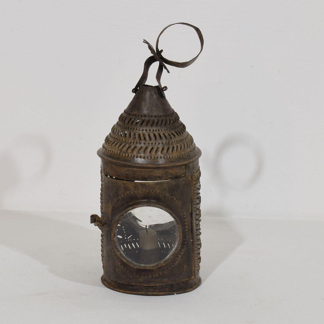 Beautiful and rare folk art rolled sheet iron pendant lantern with a great patina due to its high age.
The lantern has a cylindrical body with a conical pediment pierced with intricate decorative perforations.
The lantern has one small door and 2