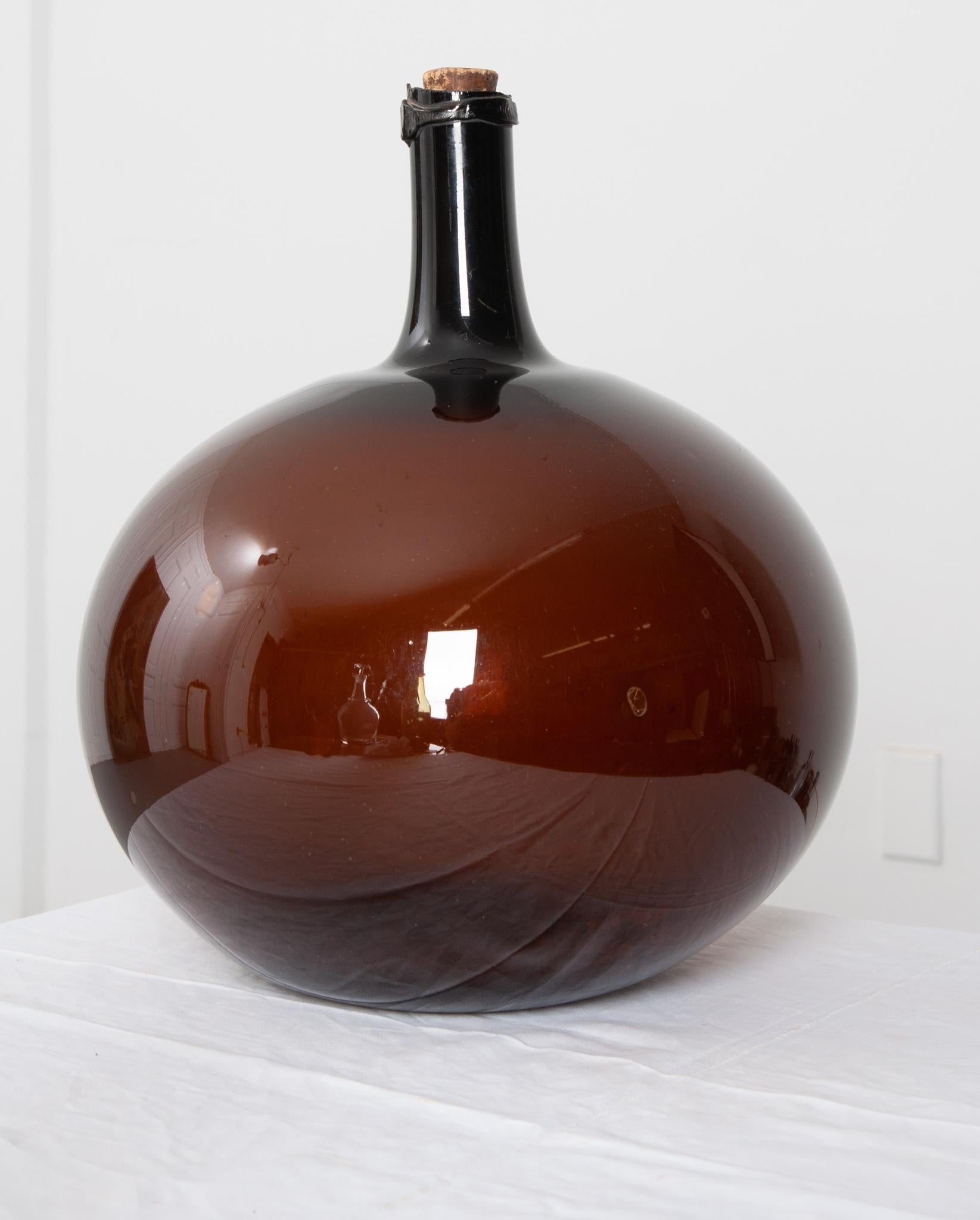 This beautiful, amber blown glass wine keg, or demijohn as they are sometimes called, remains fully intact with a cork. Still in wonderful condition, this piece would be a great addition to your space, giving it an element of texture and color. They