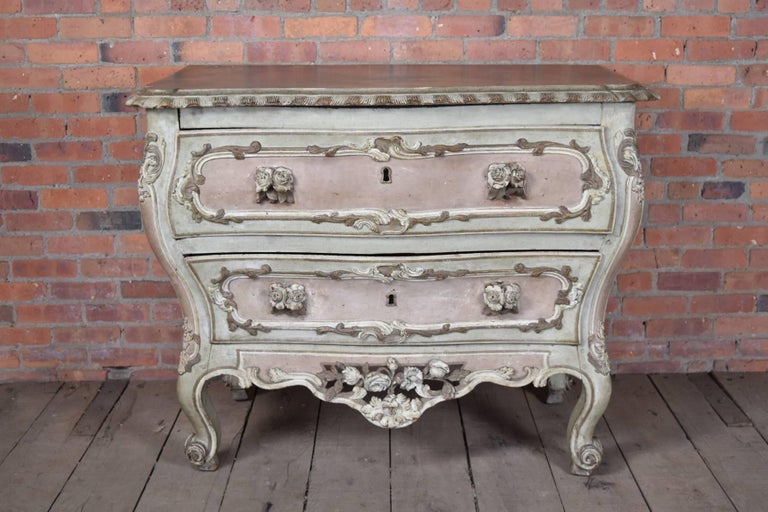 Unusual painted bombe commode with two drawers.
Exuberant form with faux marbleized top, carved decoration and very unusual floral carved drawer pulls. Paint probably of later date.

