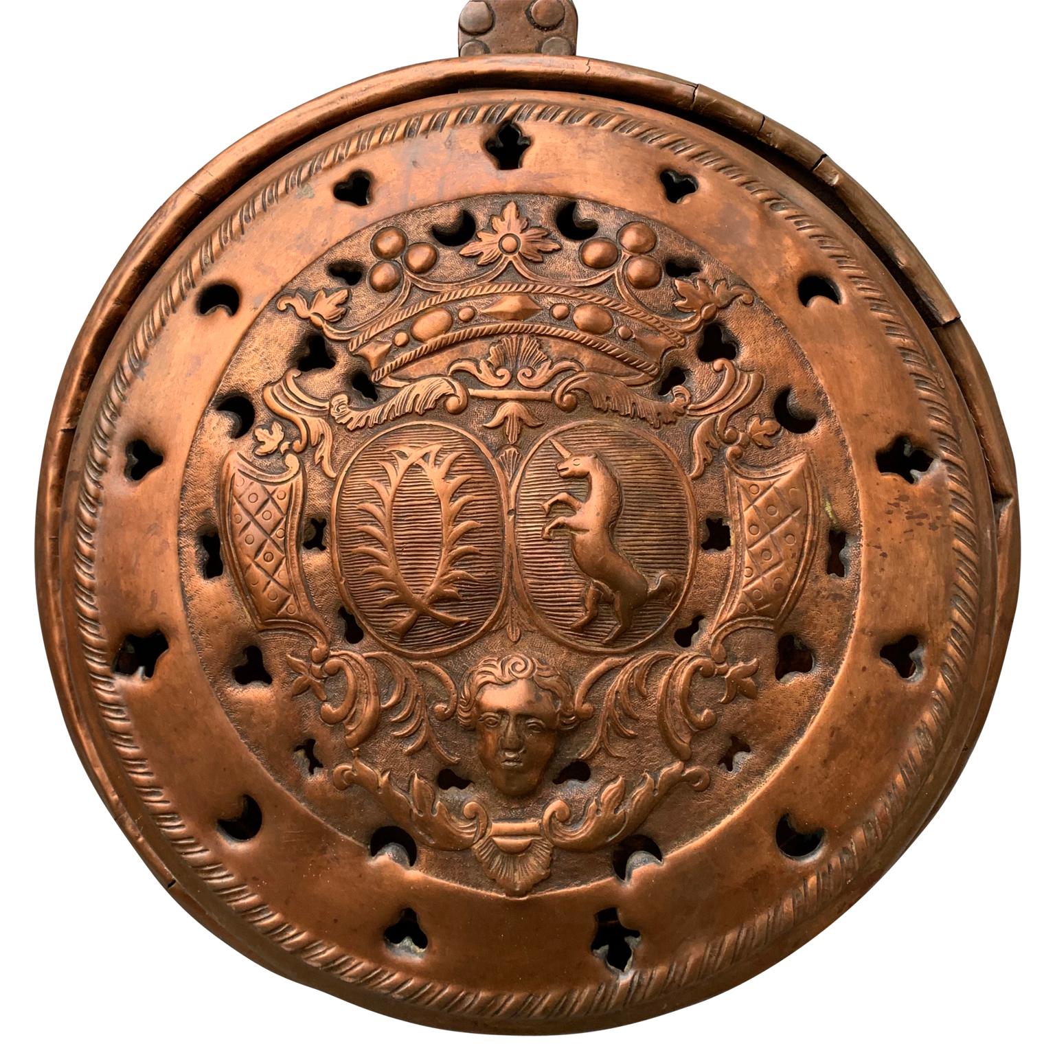 An 18th century French bed warmer in copper with wooden handle. With the hammered decoration of a noble family own coat-of-arms. The last is showing an unicorn which is a symbol for freedom, purity, magic and innocence and two laurel branches that