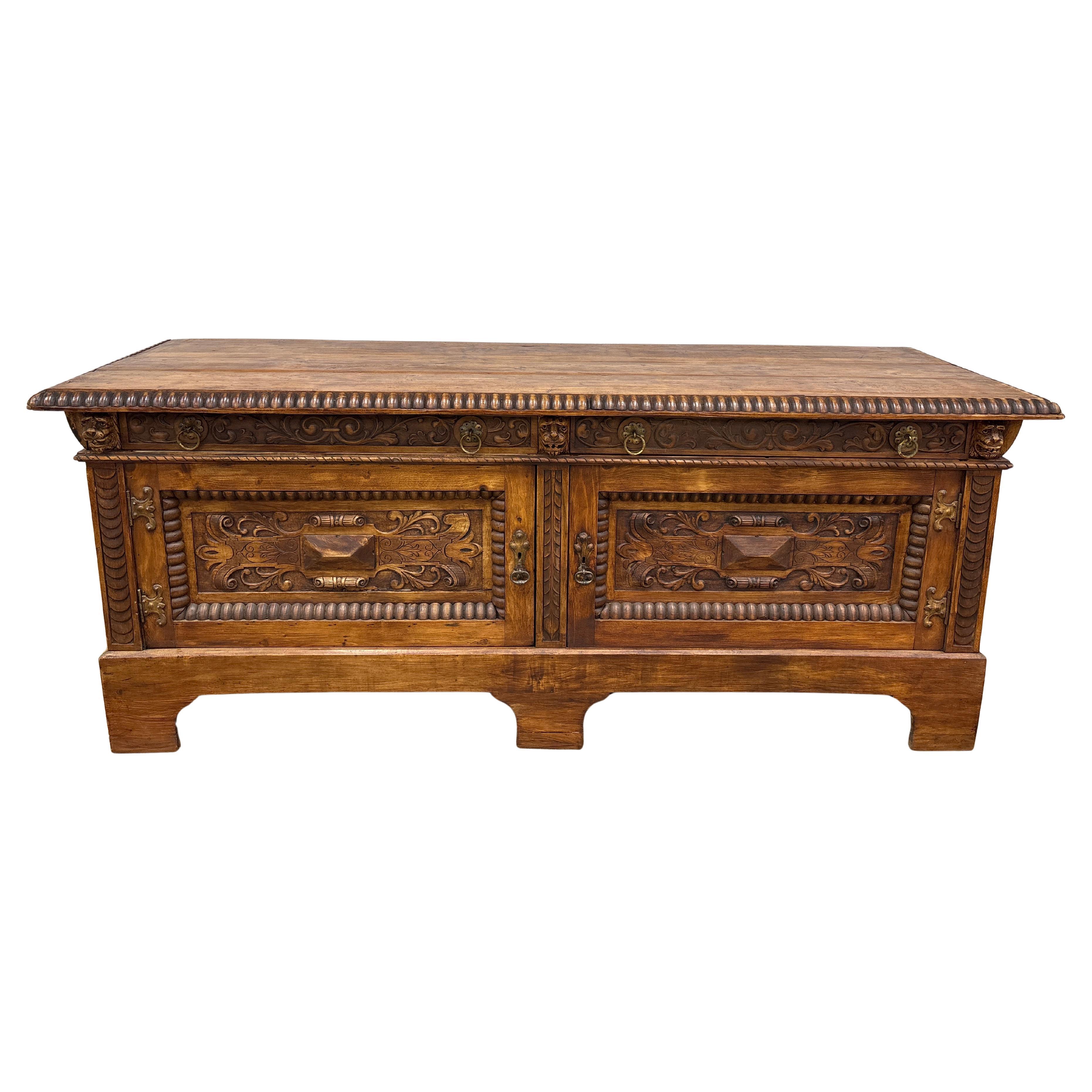 Questa lunga credenza Buffet è riccamente intagliata sul fronte e sui lati. Ha 2 cassetti. Proviene dal confine tra Francia e Spagna.