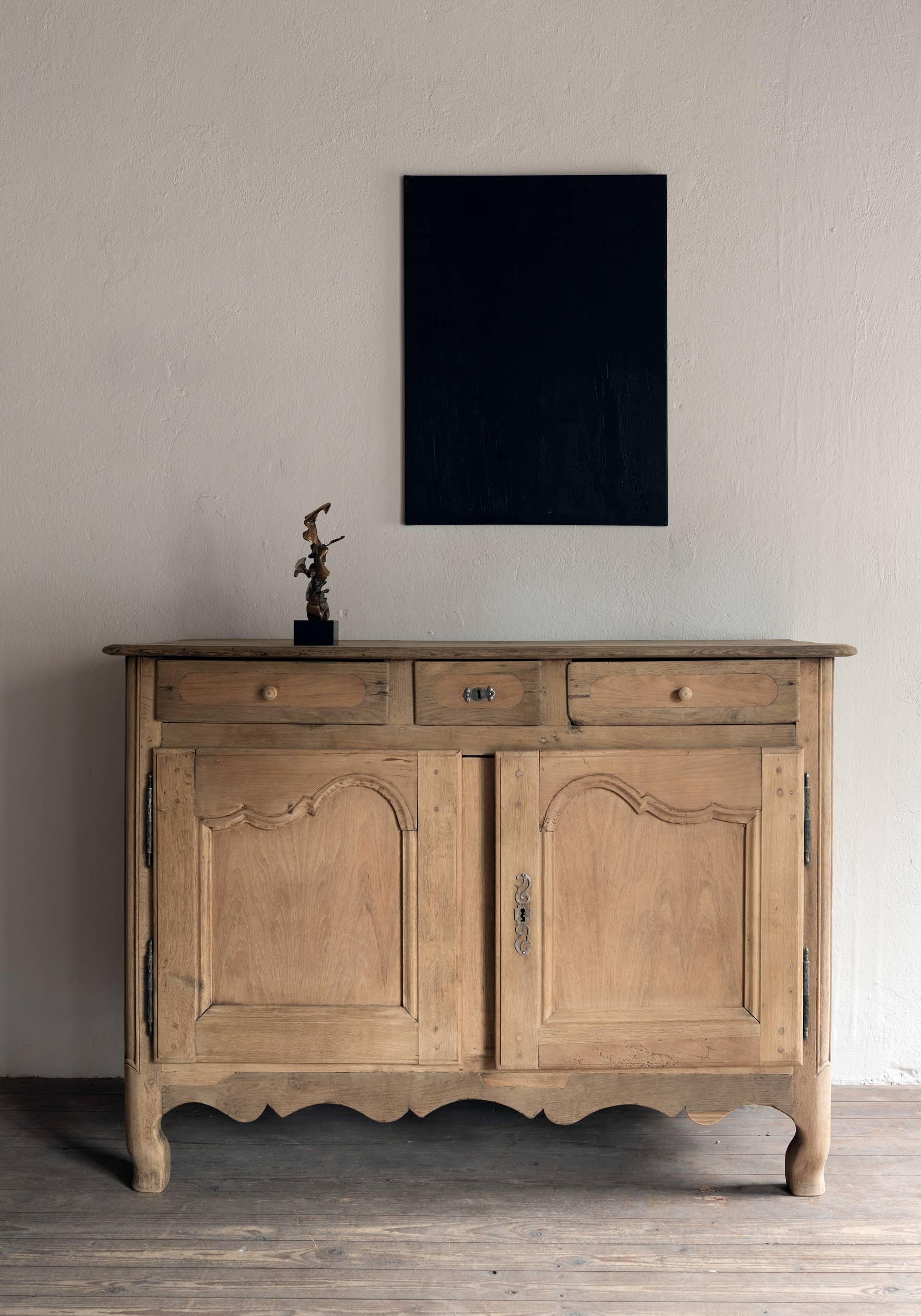 A simple and elegant bleached oak buffet, the doors with elegant restrained Louis XV carvings.