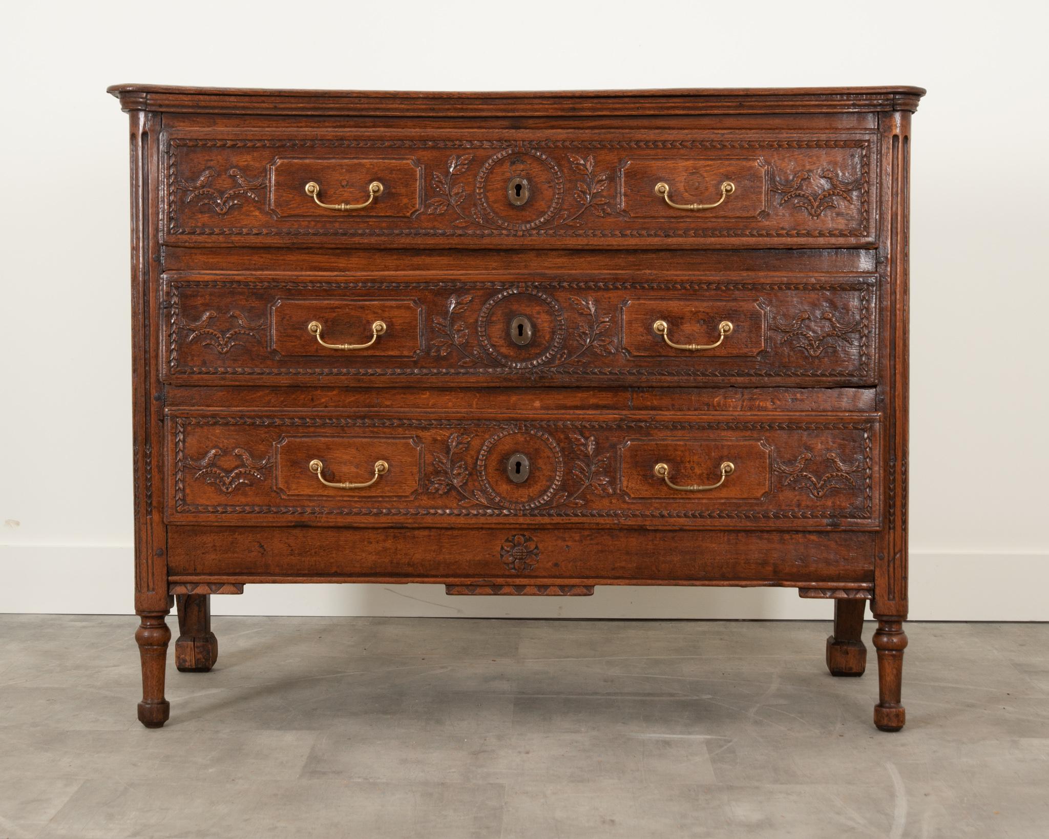 A handsome and impressive French commode from the 1780’s. Made of solid oak, this case piece is simply designed from the Louis XVI style. The drawers have intricately hand carved designs of birds and flowers with more recent drawer pulls. All joints