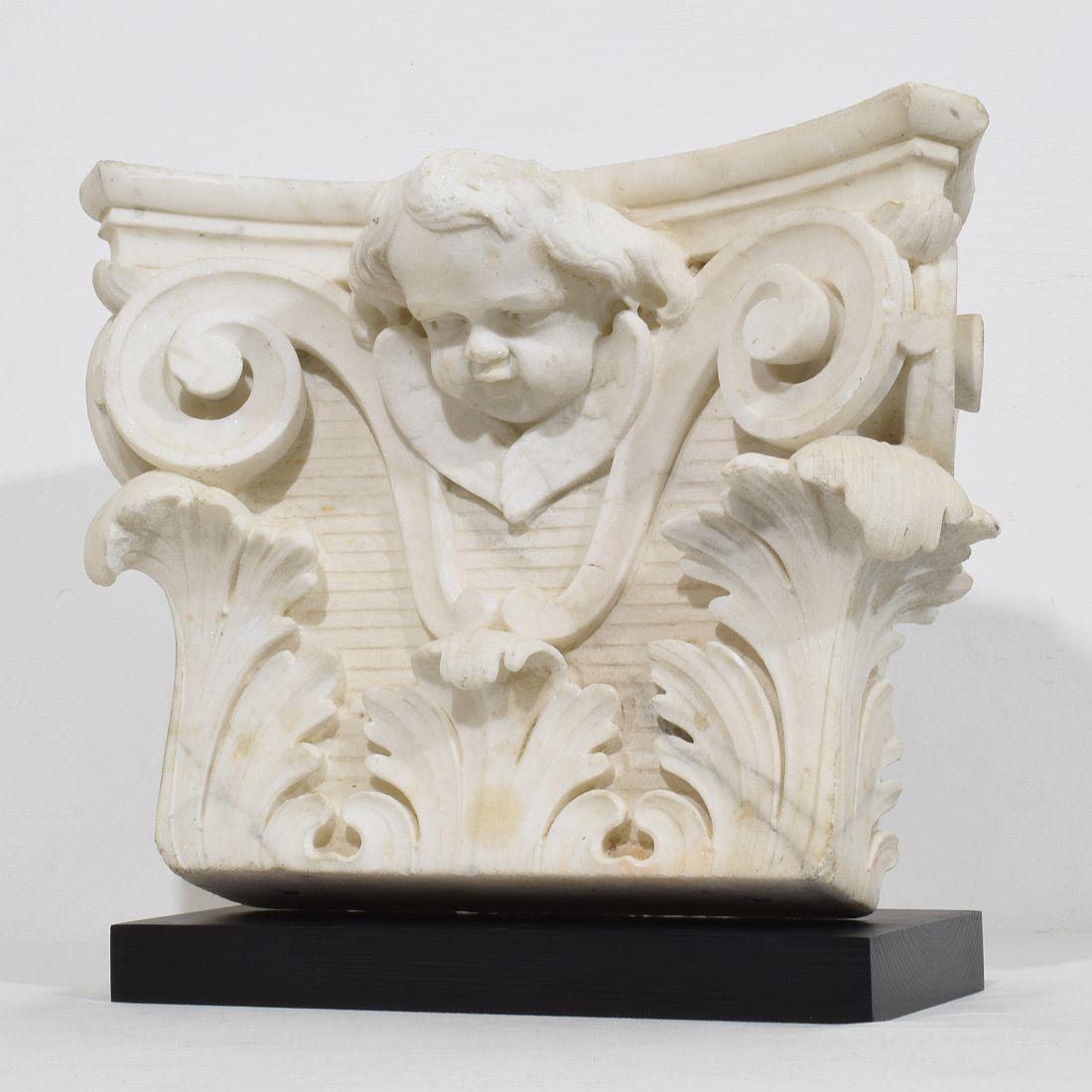 Spectacular hand-carved white marble capital with angel head. 
Beautiful weathered white marble .
France circa 1750
Weathered
Measurements include the wooden pedestal