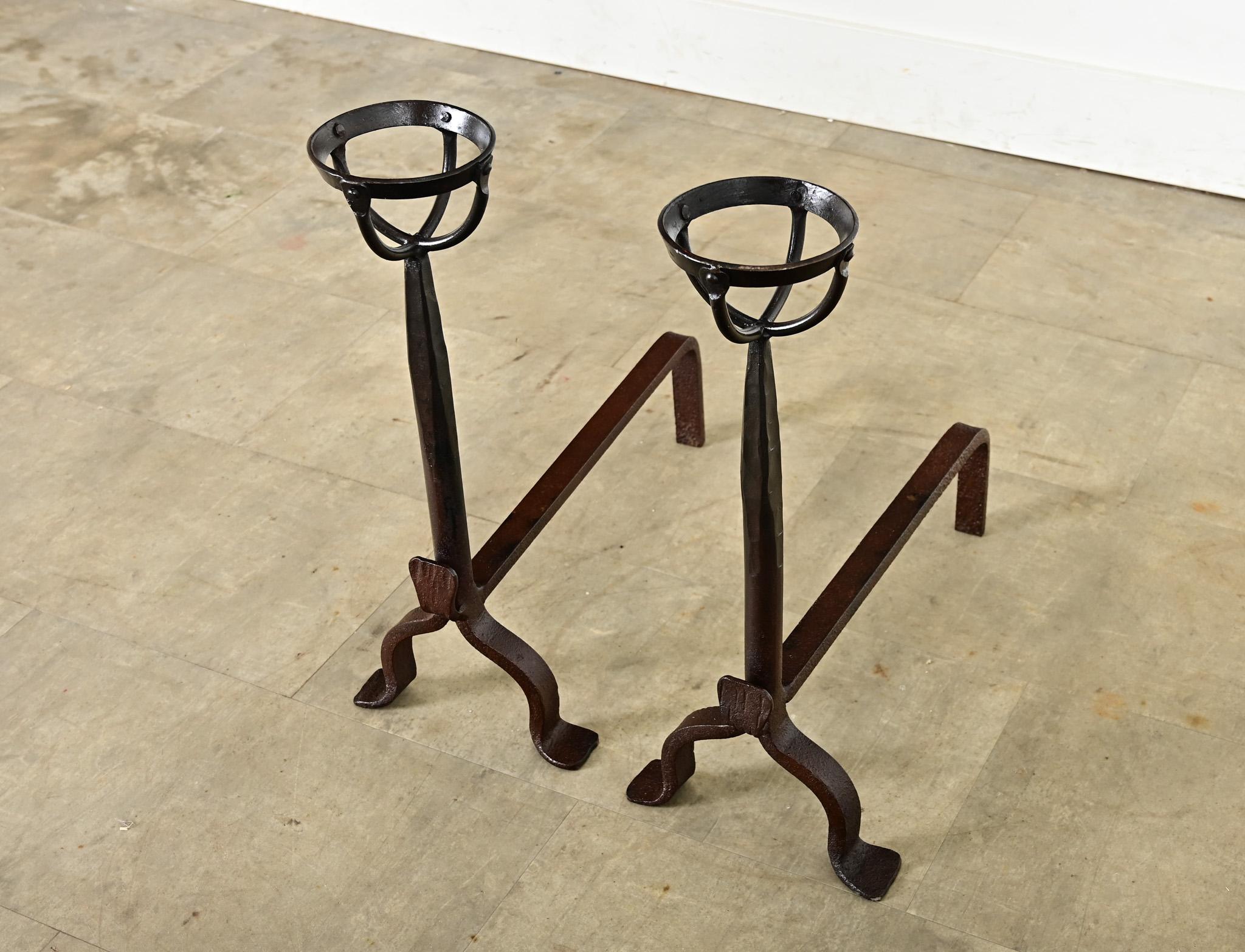 A slender pair of French 18th century hand-wrought fireplace andirons. They are Gothic-Mediterranean in style emboldened by a reddish brown patina from oxidation of the iron and centuries of exposure to high heat. Known as “landiers” in French,