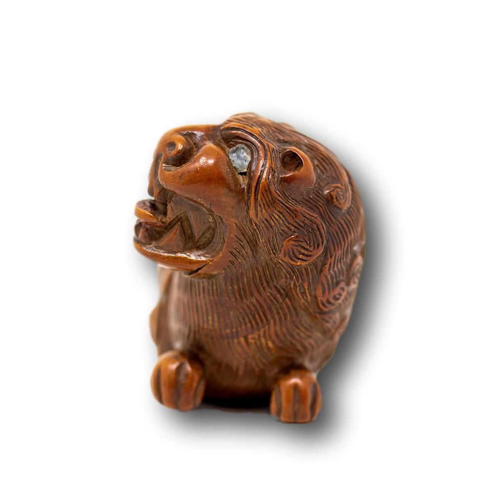 Feine und seltene kontinentale Schnupftabakdose aus Obstholz des 18. Jahrhunderts. Die Schnupftabakdose hat die Form eines liegenden Löwen mit aufgerichtetem, knurrendem Kopf und naiven Glasaugen, geschnitzter Mähne und langem Schwanz, der auf dem