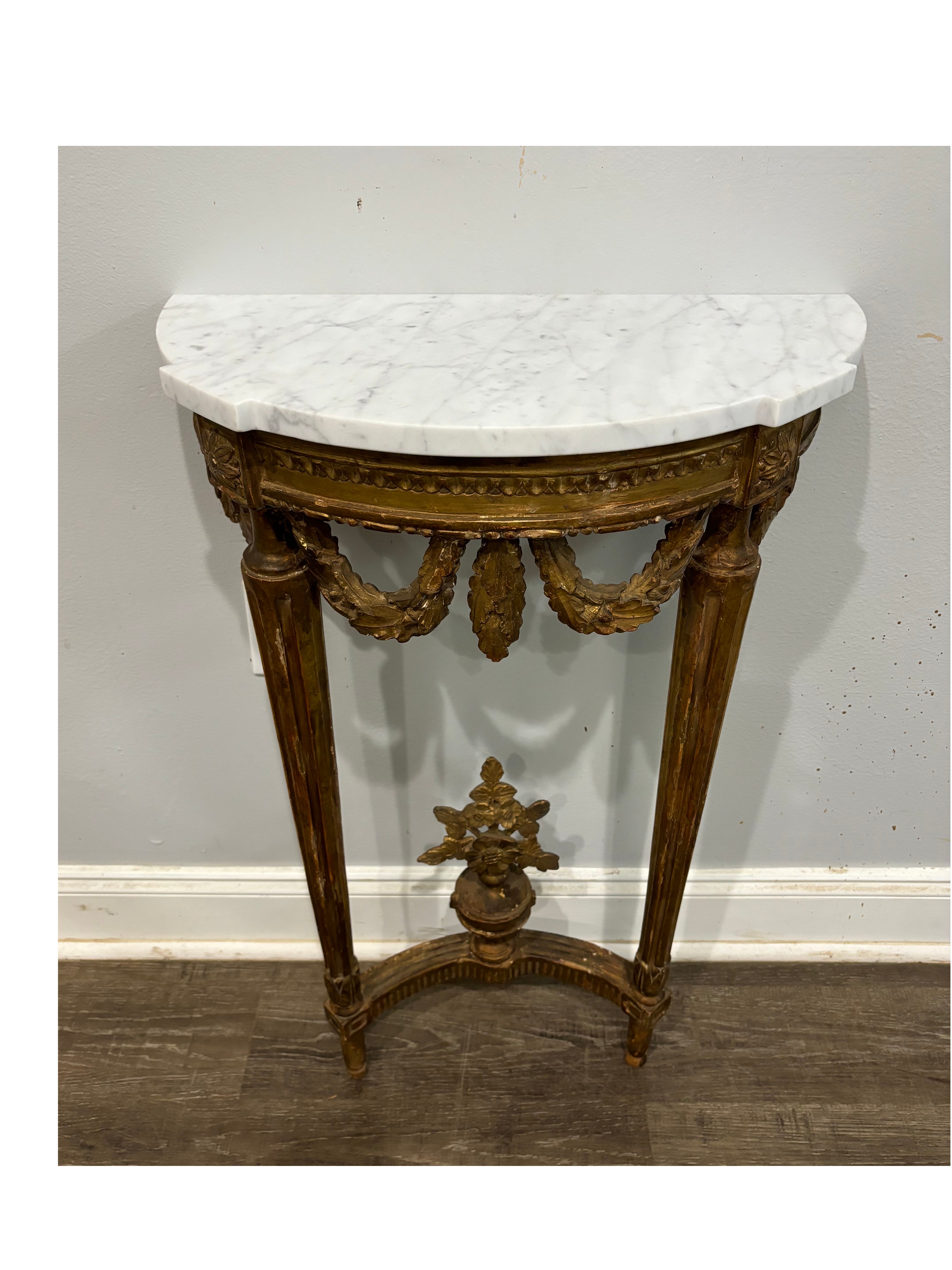 This is a very charming small Console that is standing against the wall. It is made of gilt wood with a white marble top.