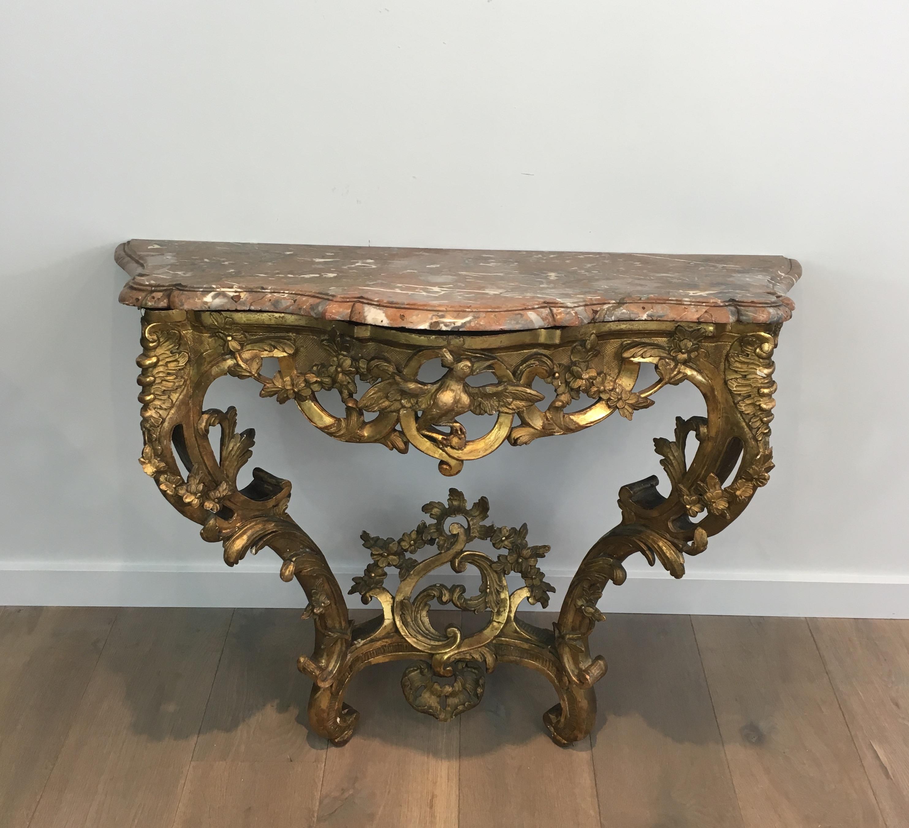 A French Louis XV period carved wood console table with marble top from the 18th century. This French console table features a shaped veined marble top sitting over a very fine and rich carved wooden base. The center of the apron showcases a bird of