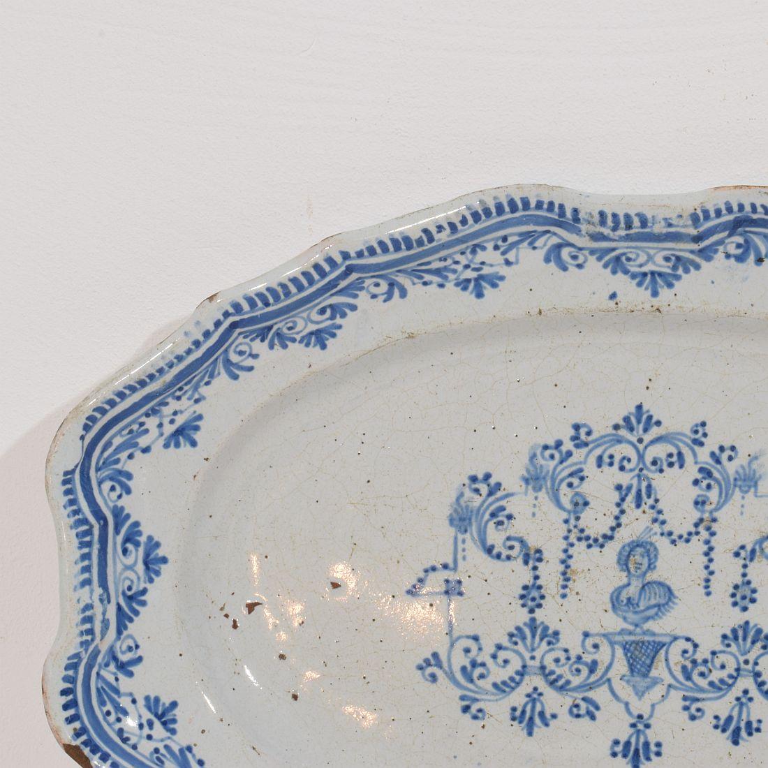 Very rare Rouen plate with beautiful blue decoration. Wonderful decorated with a bust , floral ornaments and guirlandes .France, circa 1750. Good condition
H:3,5cm  W:35cm D:23,5cm 