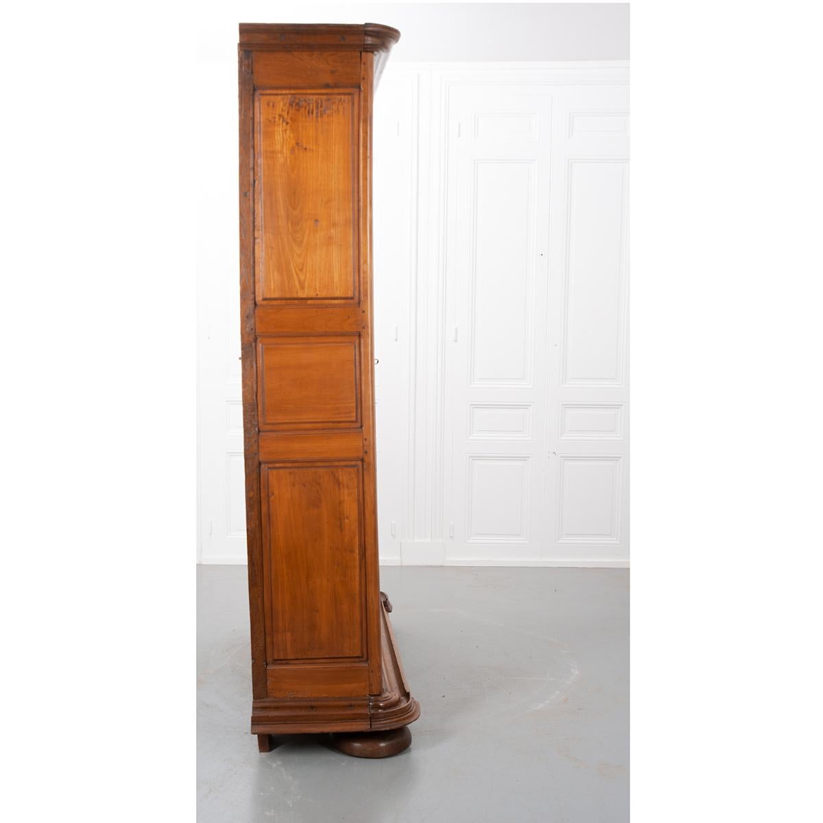 This 18th century, mixed wood French armoire is absolutely stunning. It is Gothic-style and features two tall, paneled doors on barrel hinges. One key operates the locking right door and acts as a pull. The left door latches from the inside to keep