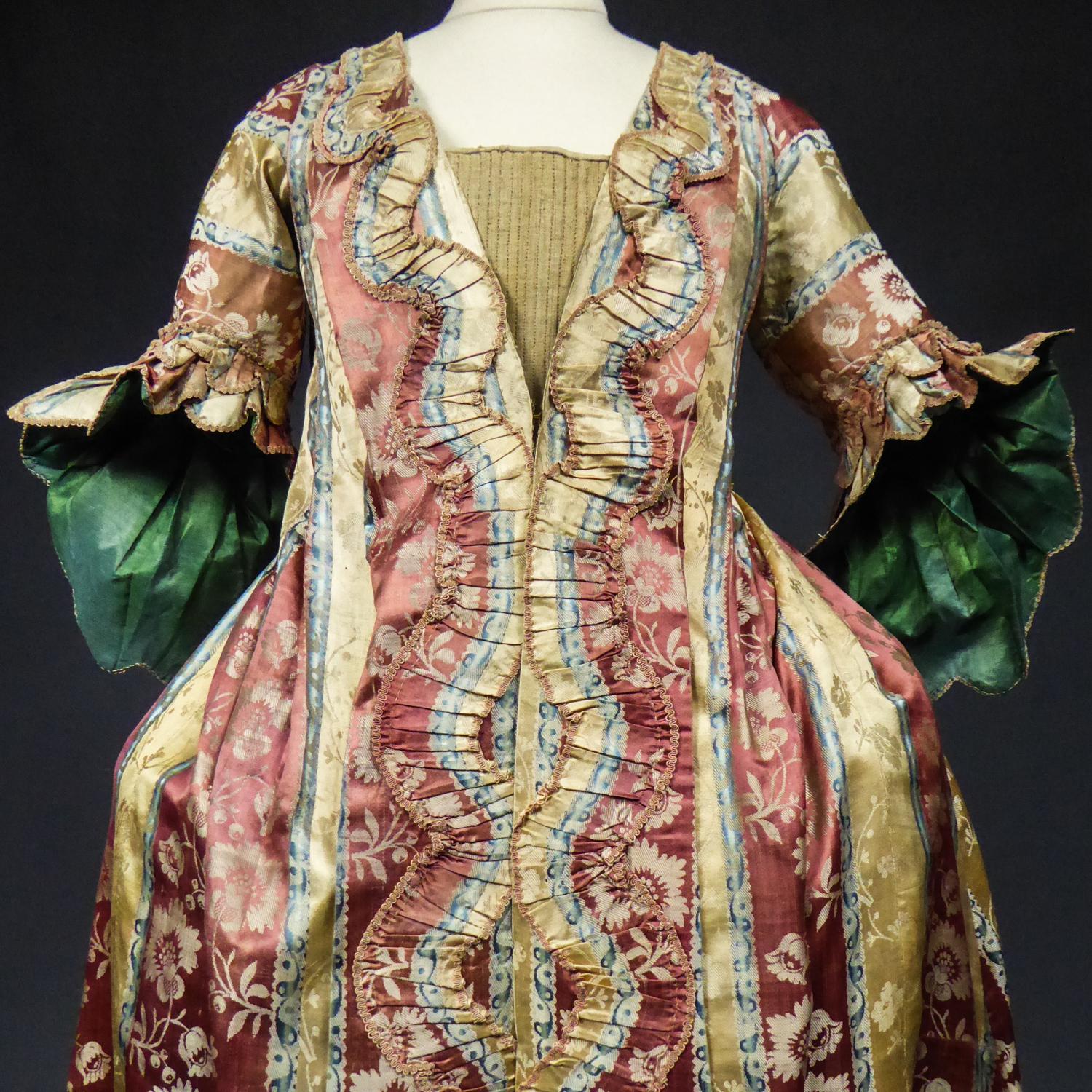 Circa 1740/1760
France

Rare Louis XV robe volante (or flying dress) or interior coat between 1740 and 1760. Shaded satin damask with wide stripes adorned with floral garlands in brick, sky-blue, straw-yellow and cream tones. Typical pyramidal cut