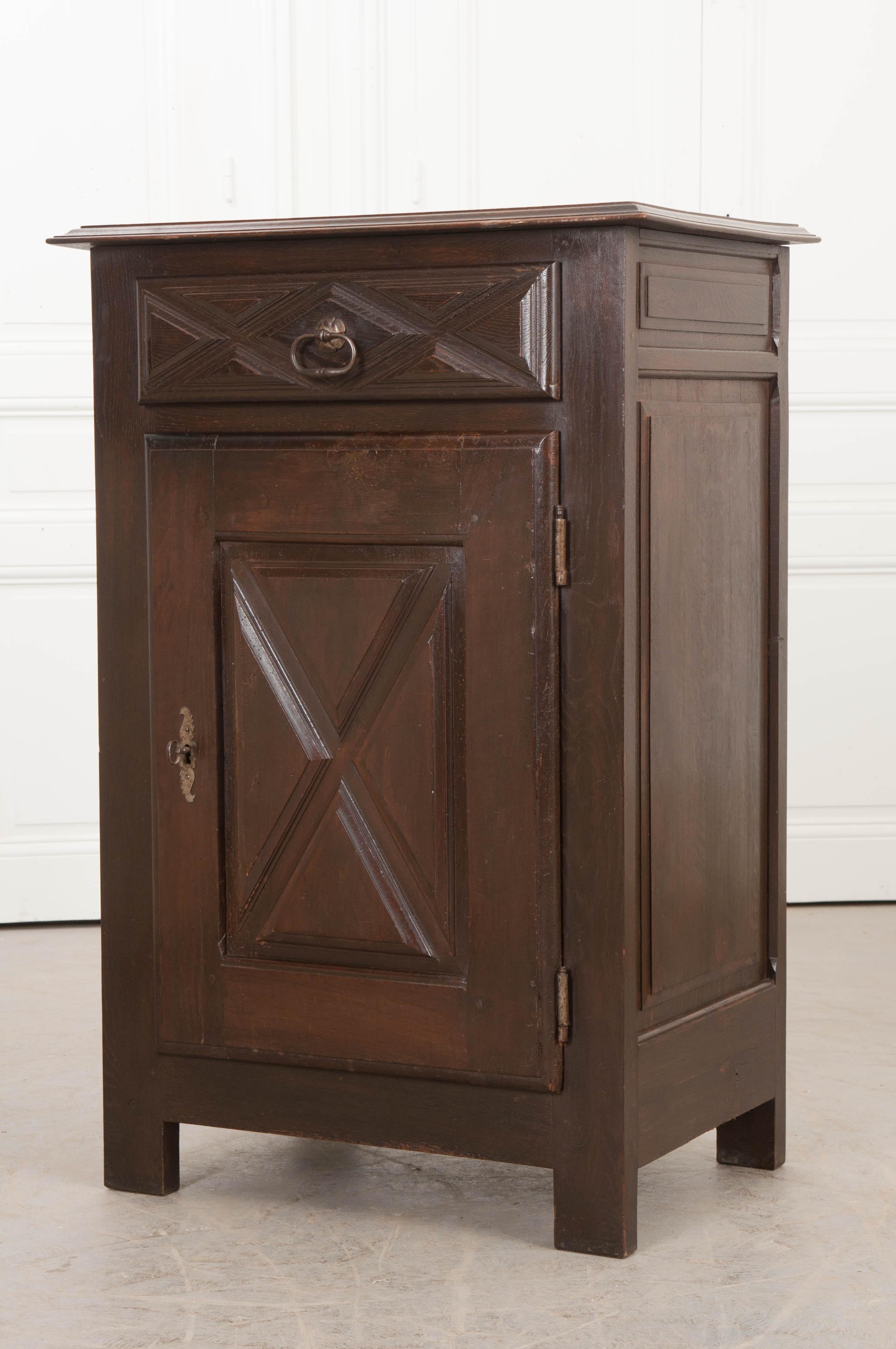 This exceptional oak confiturier is from France, circa 1880, and displays a beautiful, rich patina. It features a single “X”-carved drawer with an oblong steel pull over a like-carved locking door with handcut steel escutcheon and steel barrel