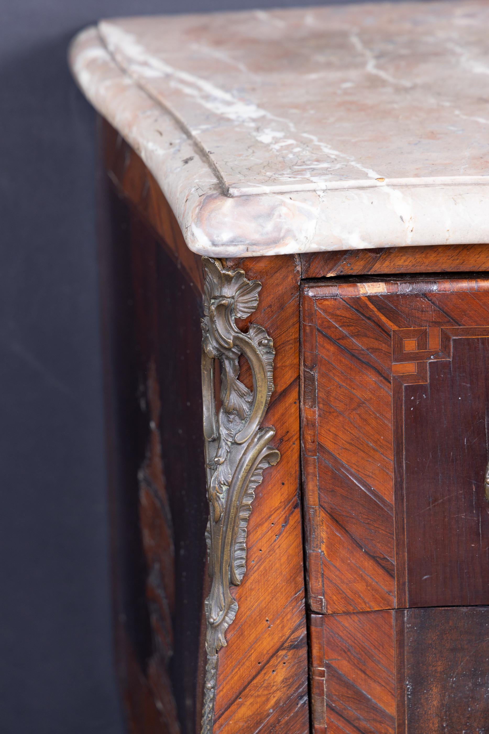 Commode à deux tiroirs Louis XV Bombé du XVIIIe siècle avec dessus en marbre, écusson et montures en bronze.  Les façades des tiroirs sont  lourdement incrusté de marqueterie de violons, tambours, cors, partitions, centré avec une paire de carquois