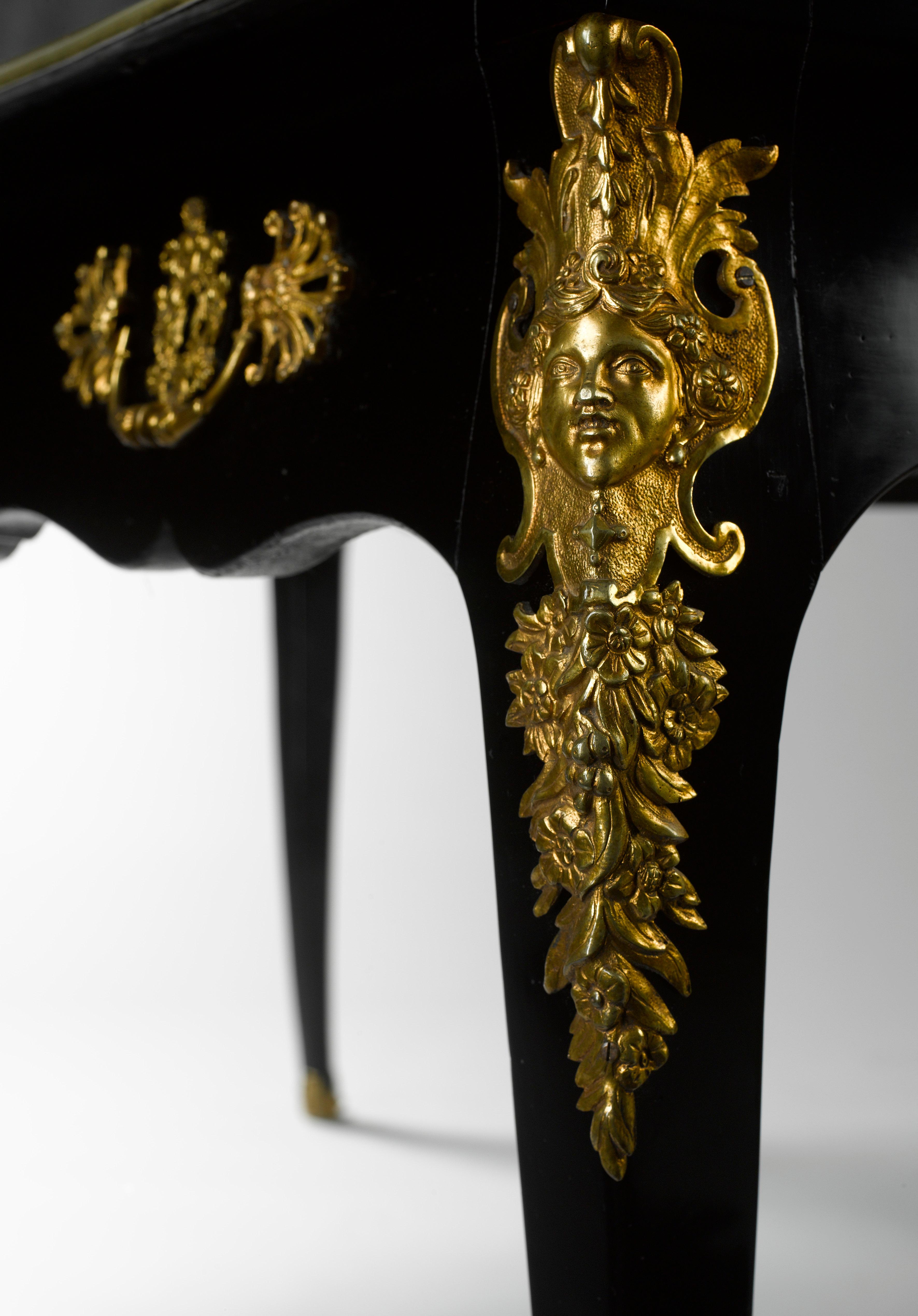 Une imposante table à écrire Louis XV en ébène avec des montures en bronze doré finement ciselé. Le plateau rectangulaire mouluré et étagé, garni de cuir doré d'origine, surmontant trois tiroirs en frise avec poignées et écussons en bronze doré, le