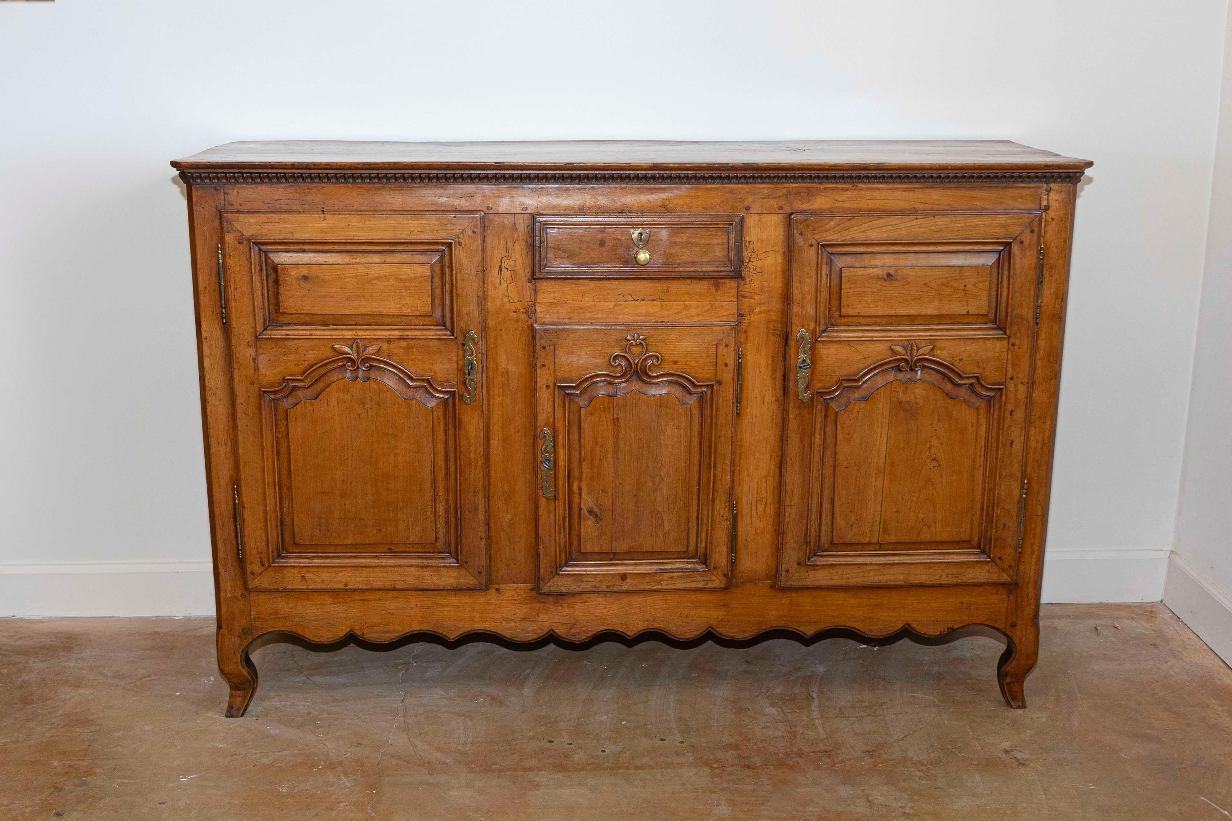 Enfilade francese in ciliegio Luigi XV del XVIII secolo con cassetto singolo e tre ante. Questo buffet lungo francese della seconda metà del XVIII secolo presenta un piano rettangolare a tre assi con angoli inclinati su un delicato fregio a