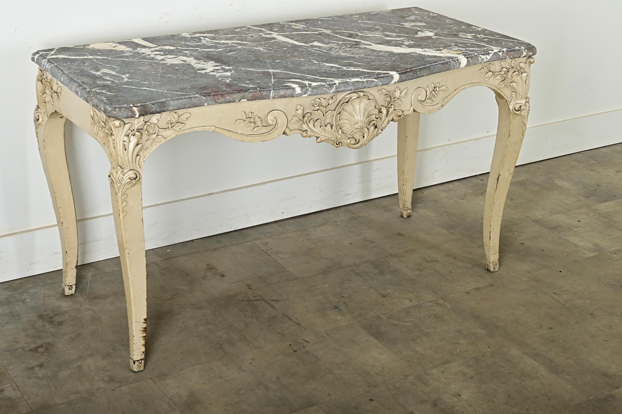 Fabulous Louis XV period console table of stunning marble top and intricately carved frame. The gray marble slab is elegantly shaped to a bowed front that aligns perfectly with the sensual curves of the base; the stone shows painterly veining of