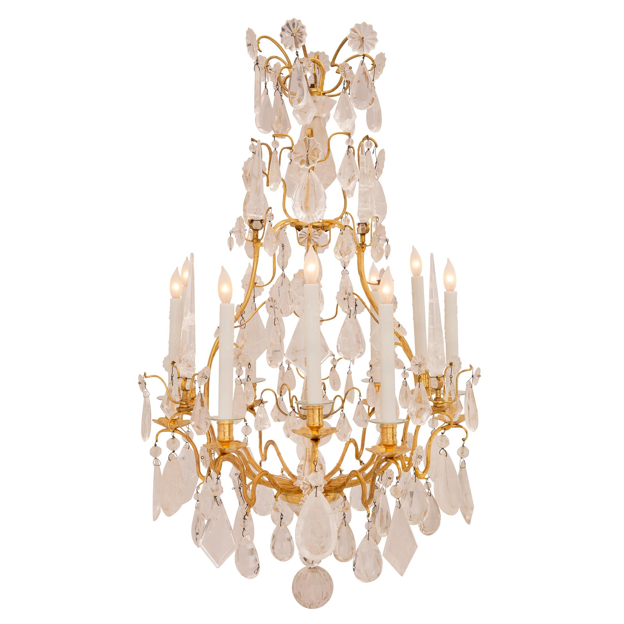 Superbe lustre en bronze doré et cristal de roche d'époque Louis XV du XVIIIe siècle. Le lustre à neuf branches est centré par un magnifique pendentif boule en cristal de roche massif parmi d'autres superbes pendentifs en forme de goutte d'eau. Les