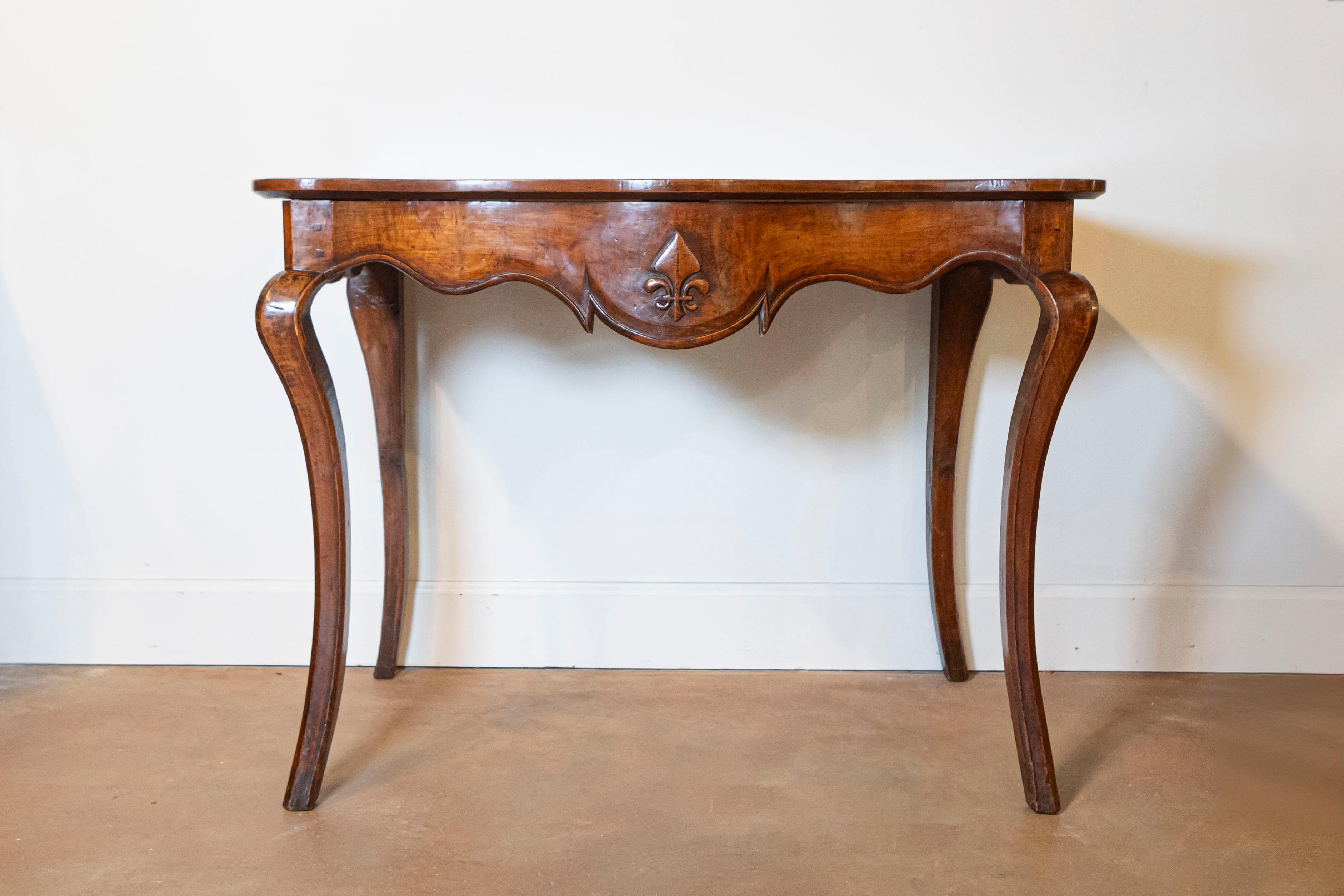 A French Louis XV period Provençale console table from the 18th century, with scalloped apron, stylized fleur-de-lys and cabriole legs. Born in Provence during the reign of King Louis XV le Bienaimé (the Beloved), this exquisite console table