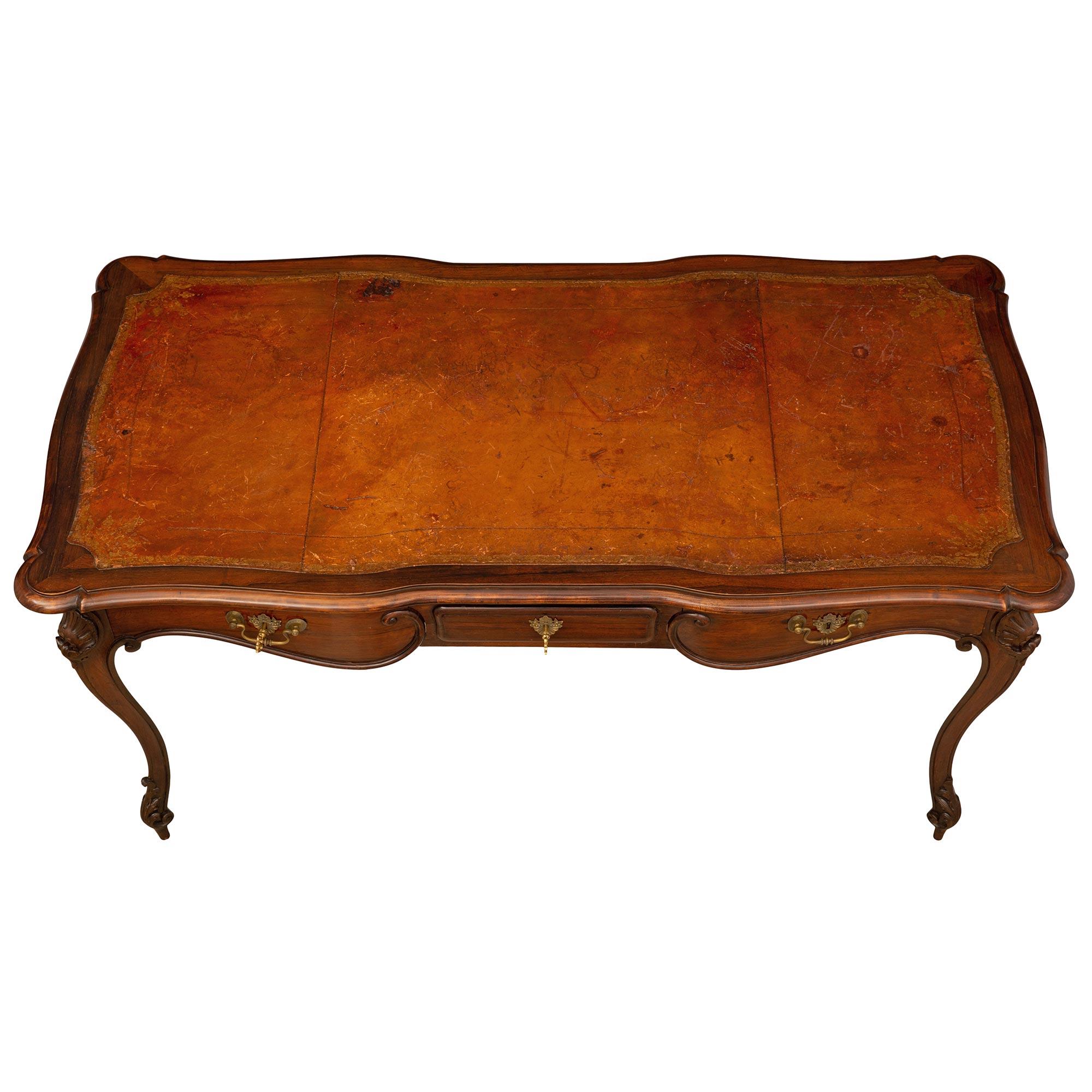 A most elegant French 18th century Louis XV period Rosewood and bronze desk. The desk is raised by four elegant tapered cabriole legs with fine scrolled acanthus leaf designed feet and beautiful richly carved seashell reserves at each corner. The