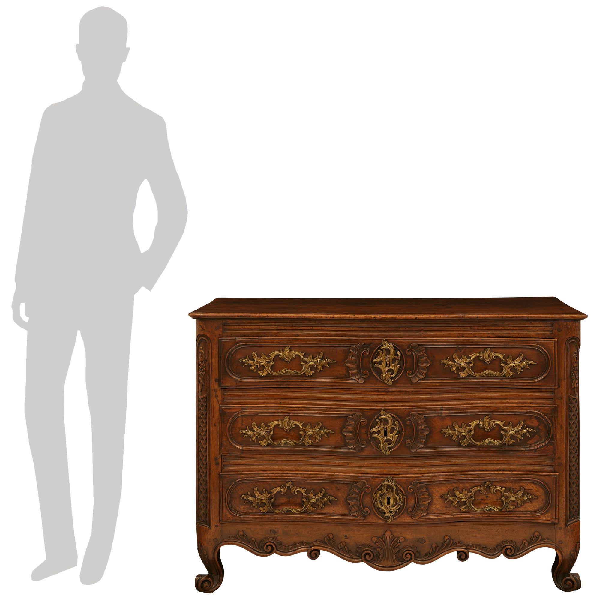 Une belle et très décorative commode en noyer et bronze d'époque Louis XV du XVIIIe siècle. Cette magnifique commode à trois tiroirs de style campagnard français repose sur des pieds en cabriole décorés de feuilles d'acanthe. Les pieds avant