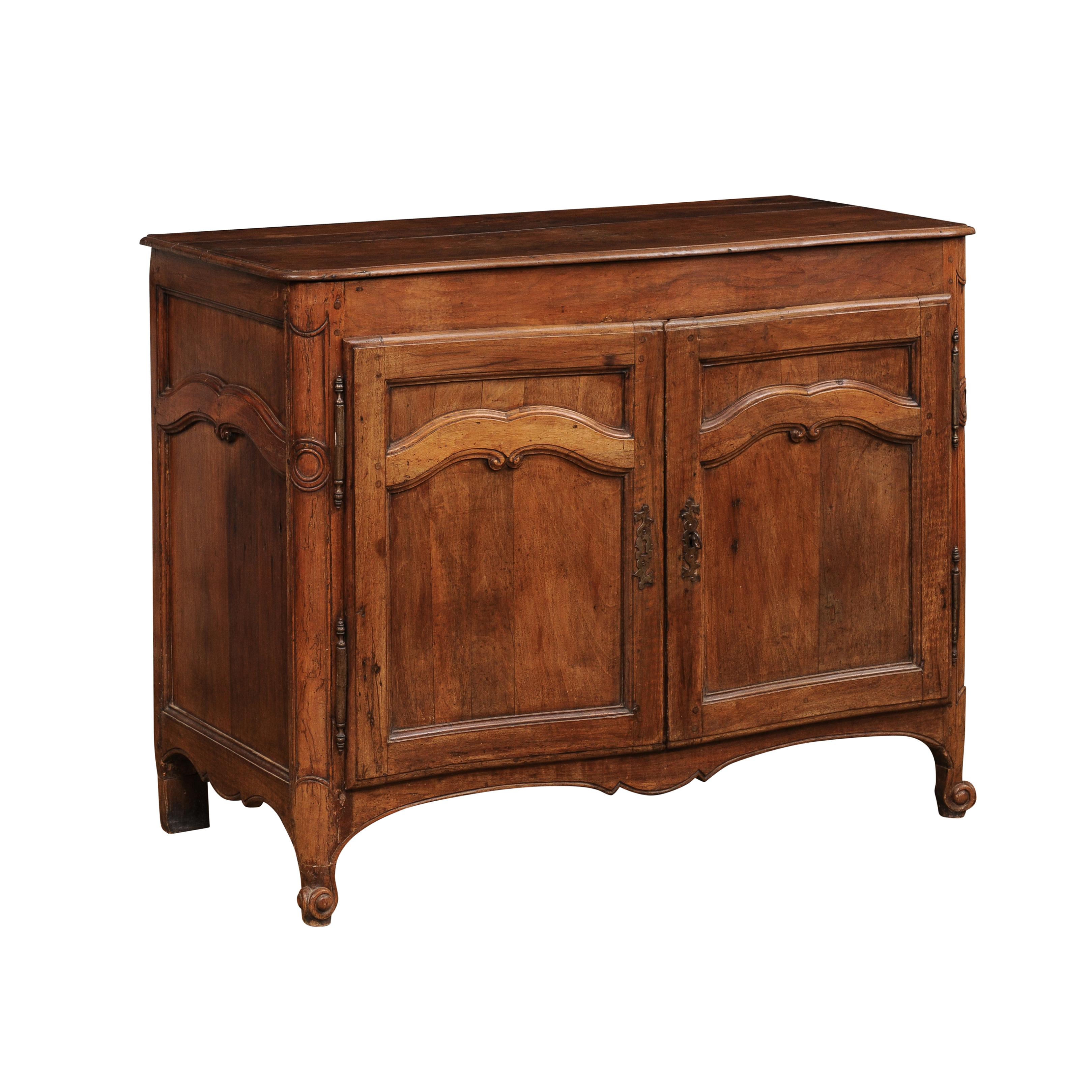 A French Louis XV period walnut buffet from the 18th century with two doors and carved arching accents. Immerse yourself in the timeless allure of French Louis XV design with this walnut buffet from the 18th century. Crafted with exquisite attention