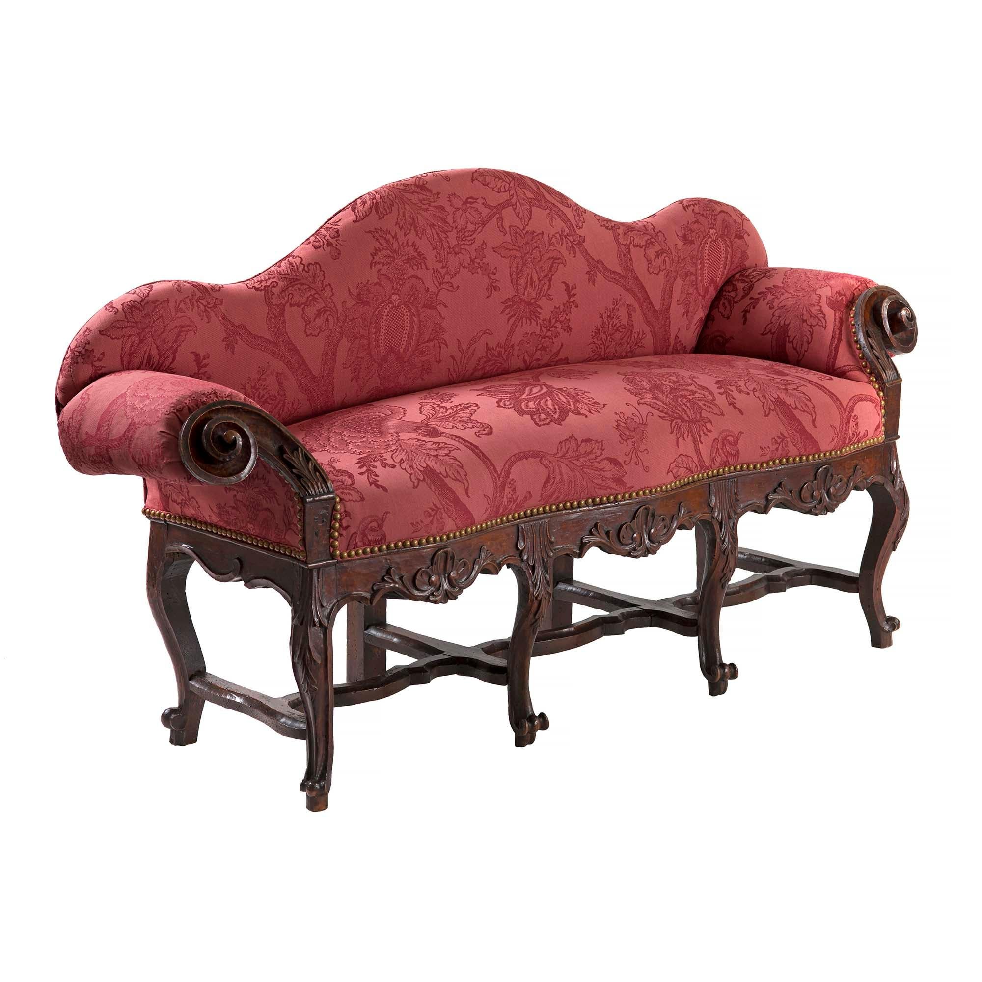 A charming small scale French 18th century Louis XV period walnut child's settee. The settee is raised by eight cabriole legs with fine scrolled feet and attached by a most decorative stretcher. Each leg displays richly carved acanthus leaves and