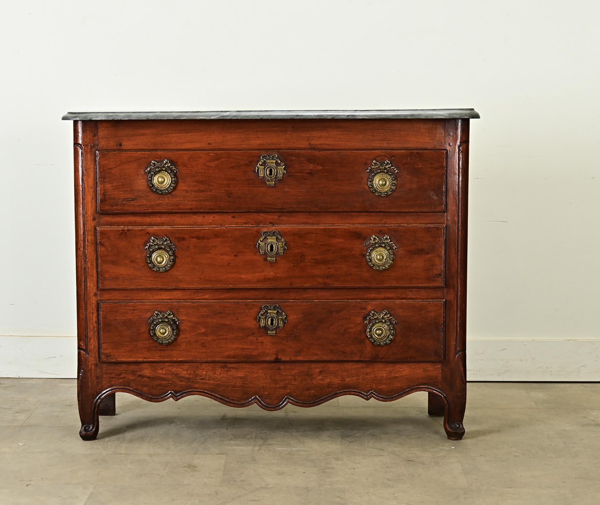 A gorgeous French mahogany commode from the 18th century, Louis XV in style, with transitional features like narrow proportions and brass hardware to complement many interior decorating tastes. The dark gray marble top is original, as evidenced by