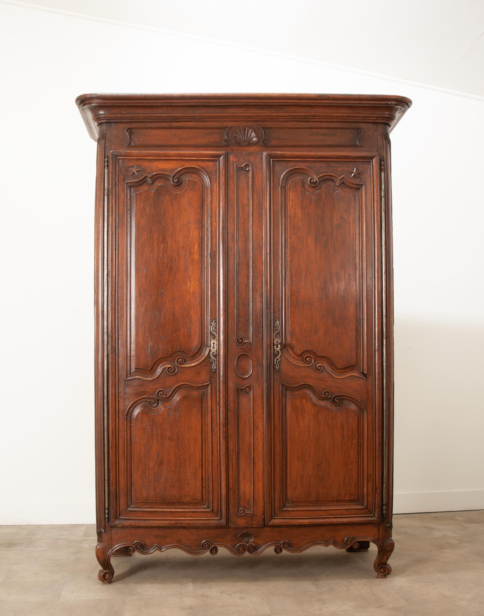 This French 18th century armoire in the Louis XV style has a fantastic dark oak finish and gorgeous hand carved details. A shaped cornice sits above elaborately paneled doors on long steel barrel hinges. This piece retains its original locking