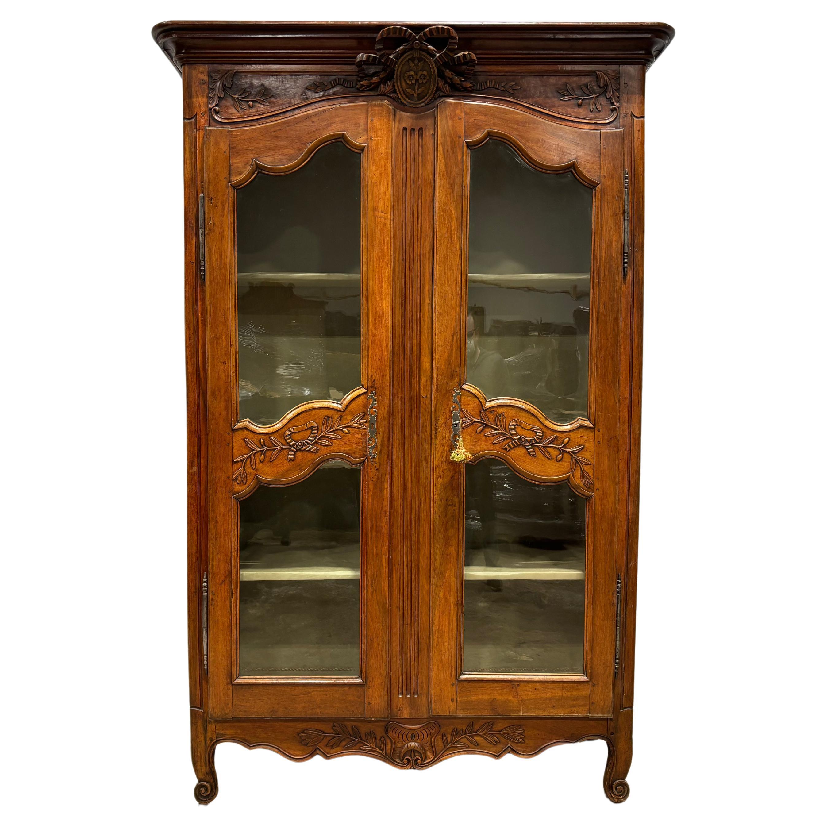 This beautiful vitrine is made of walnut with wonderful carvings, especially on the crown. The glasses are not original.